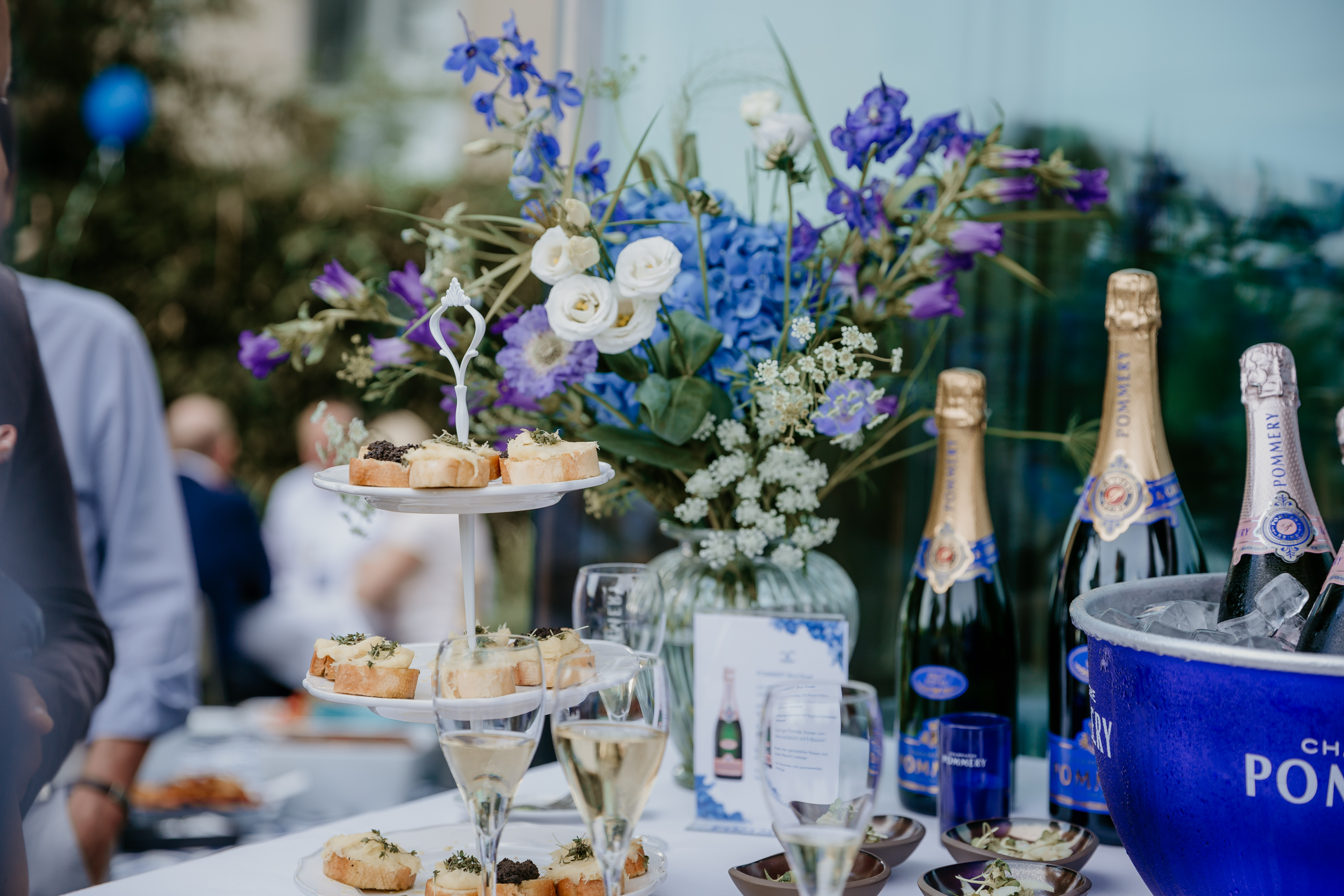 Champagnerflaschen und Canapés auf einem Tisch im Freien.