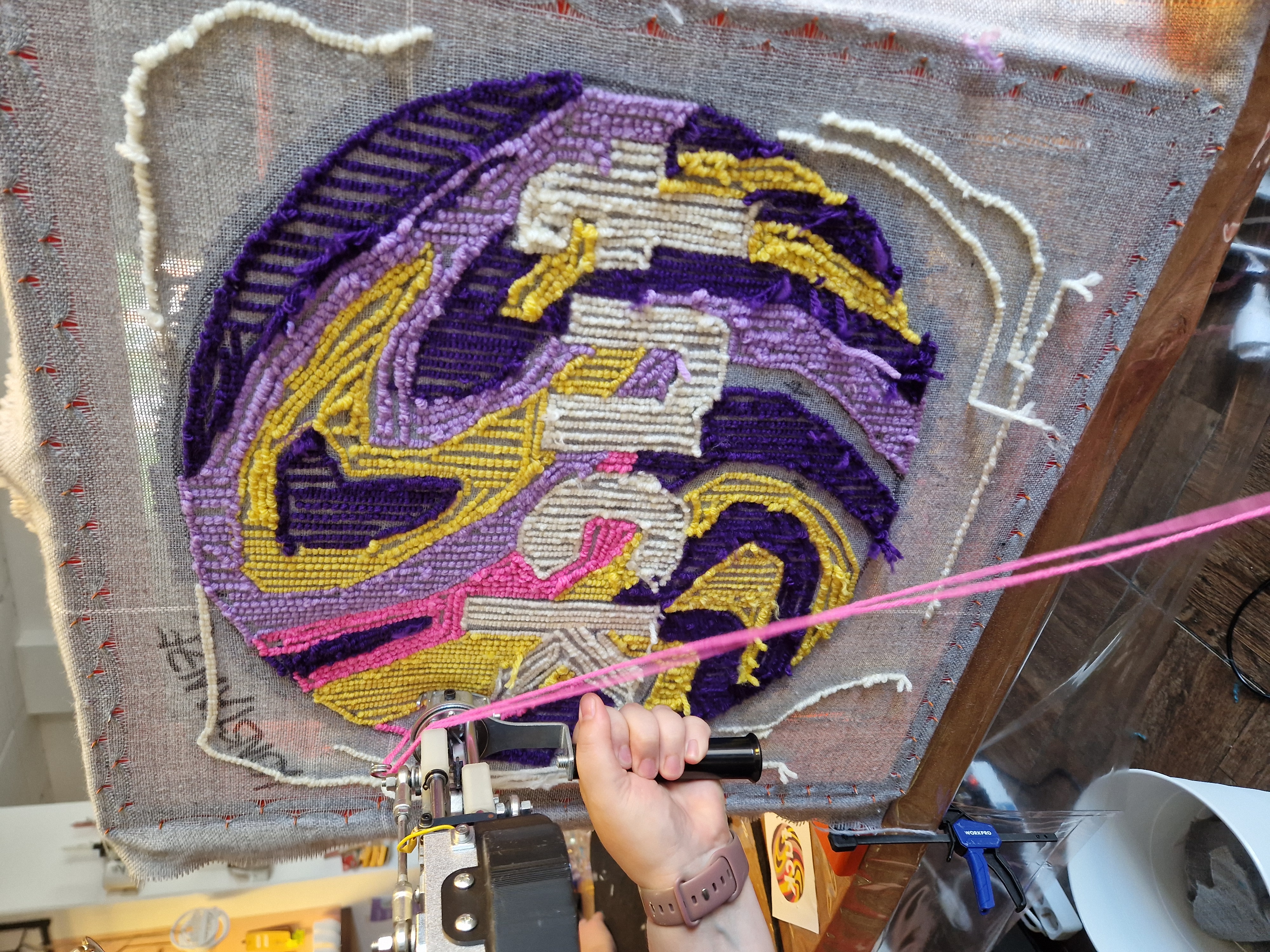 Hand benutzt Tufting-Pistole auf buntem Teppich.
