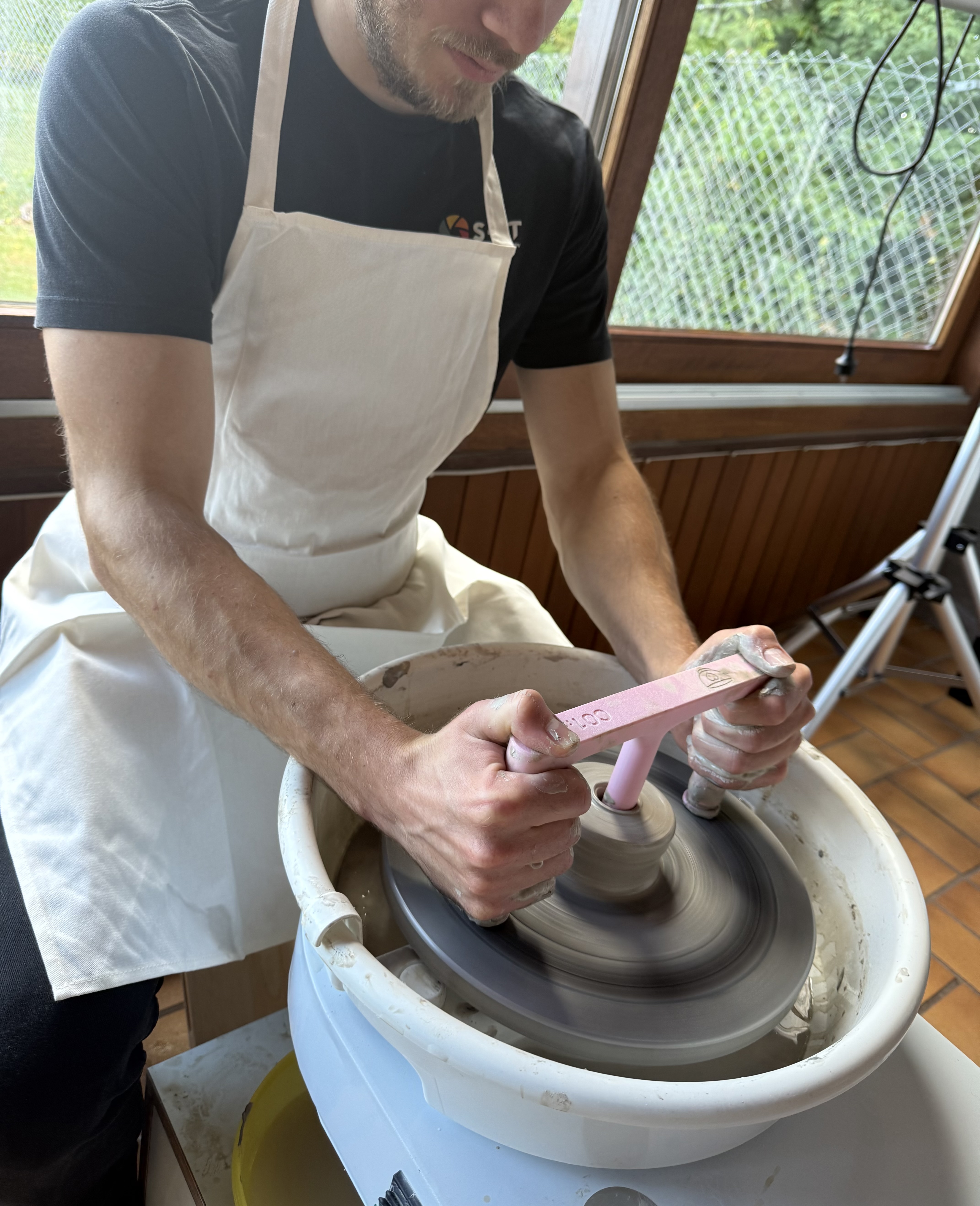 Person using pottery wheel tool indoors.