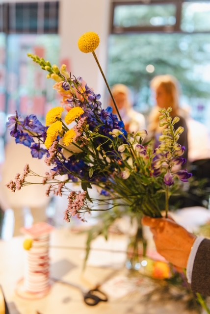 Hand hält einen bunten Blumenstrauß drinnen.