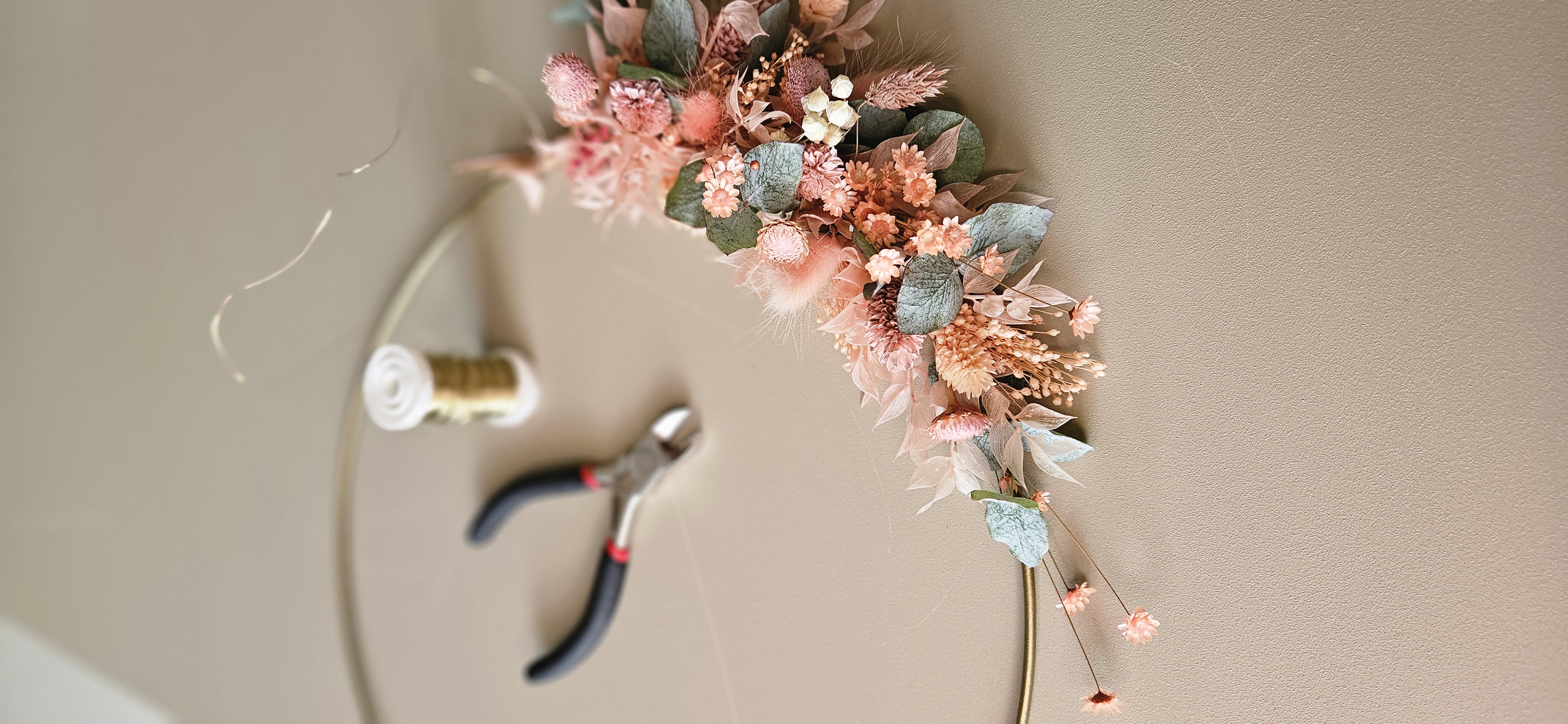 Floral arrangement on wire hoop with tools nearby.