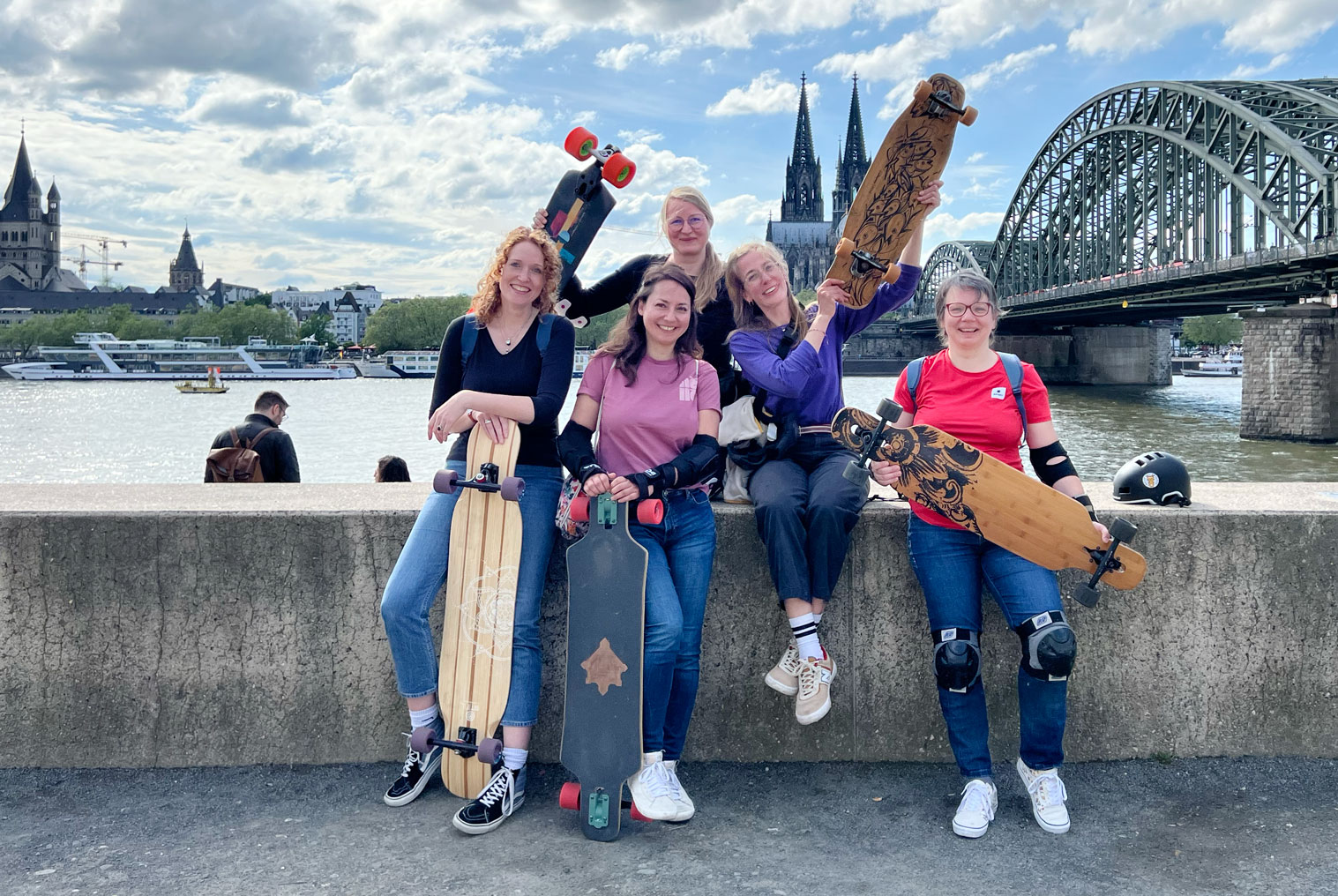 Fünf Personen mit Longboards an einer Brücke.