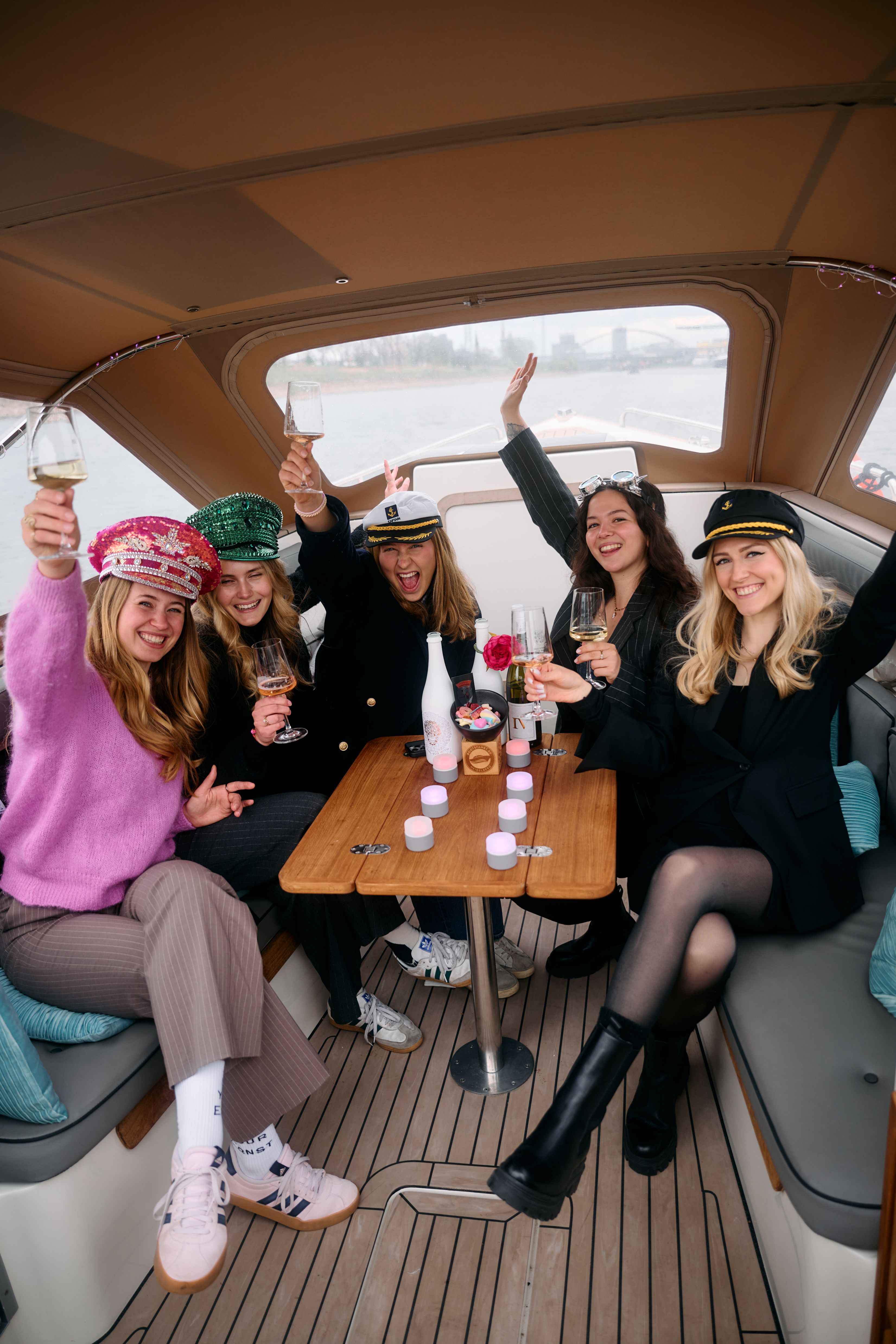 Fünf Frauen heben Gläser auf einem Boot.