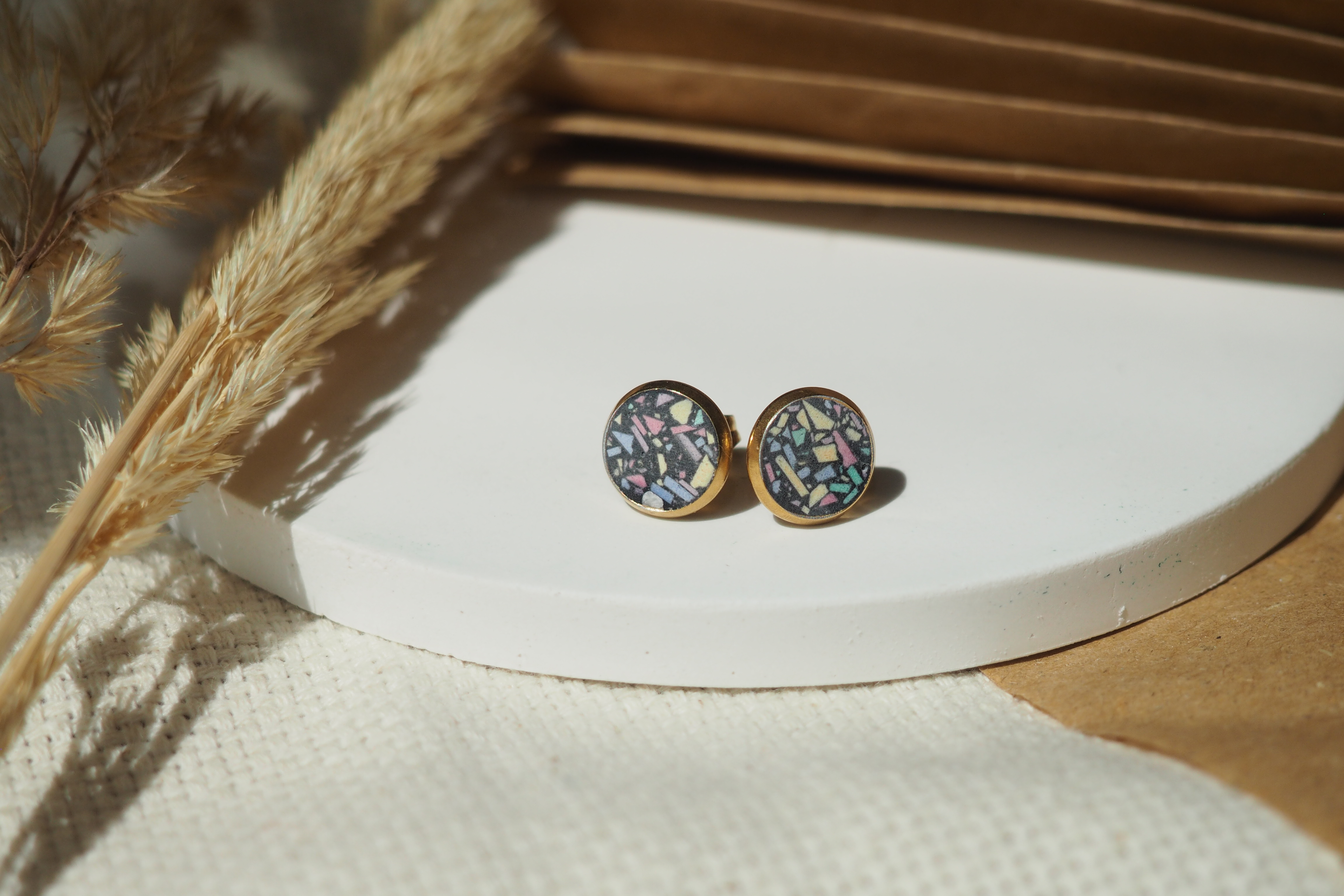 Colorful earrings on white round platform.
