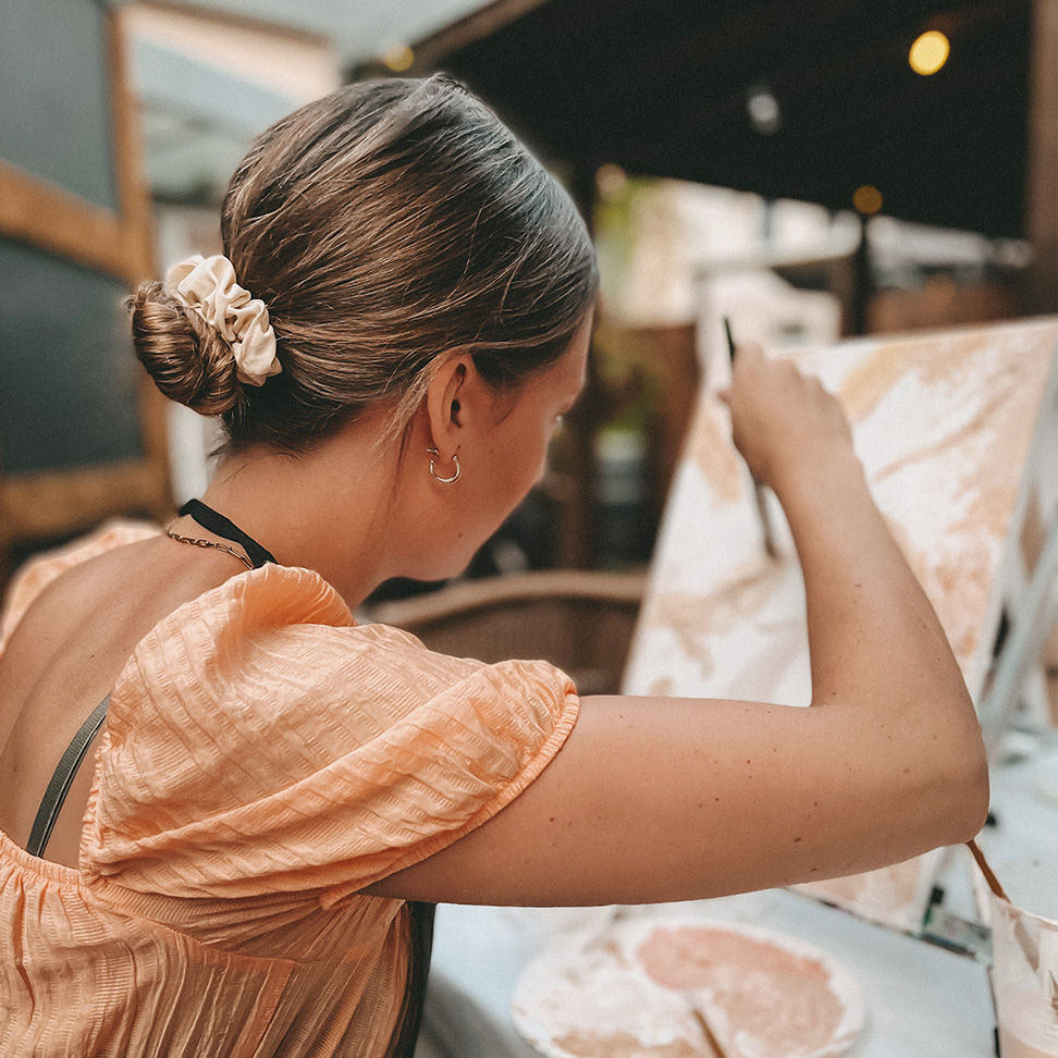 Woman painting on canvas indoors.