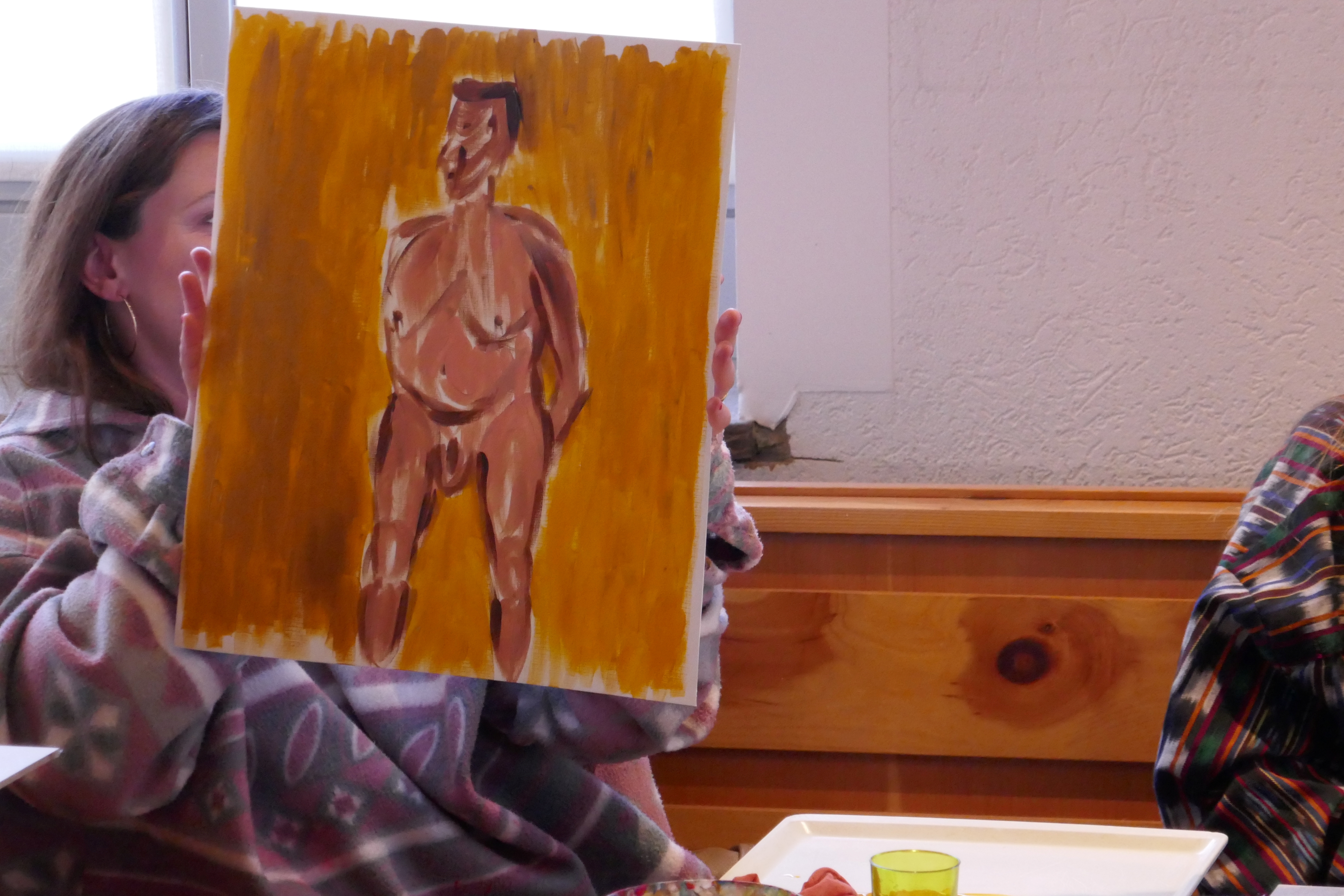 Person holding painting of nude figure indoors.