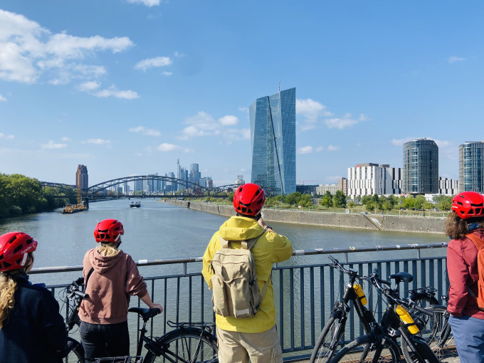 Personen mit Fahrrädern auf Brücke mit Skyline.