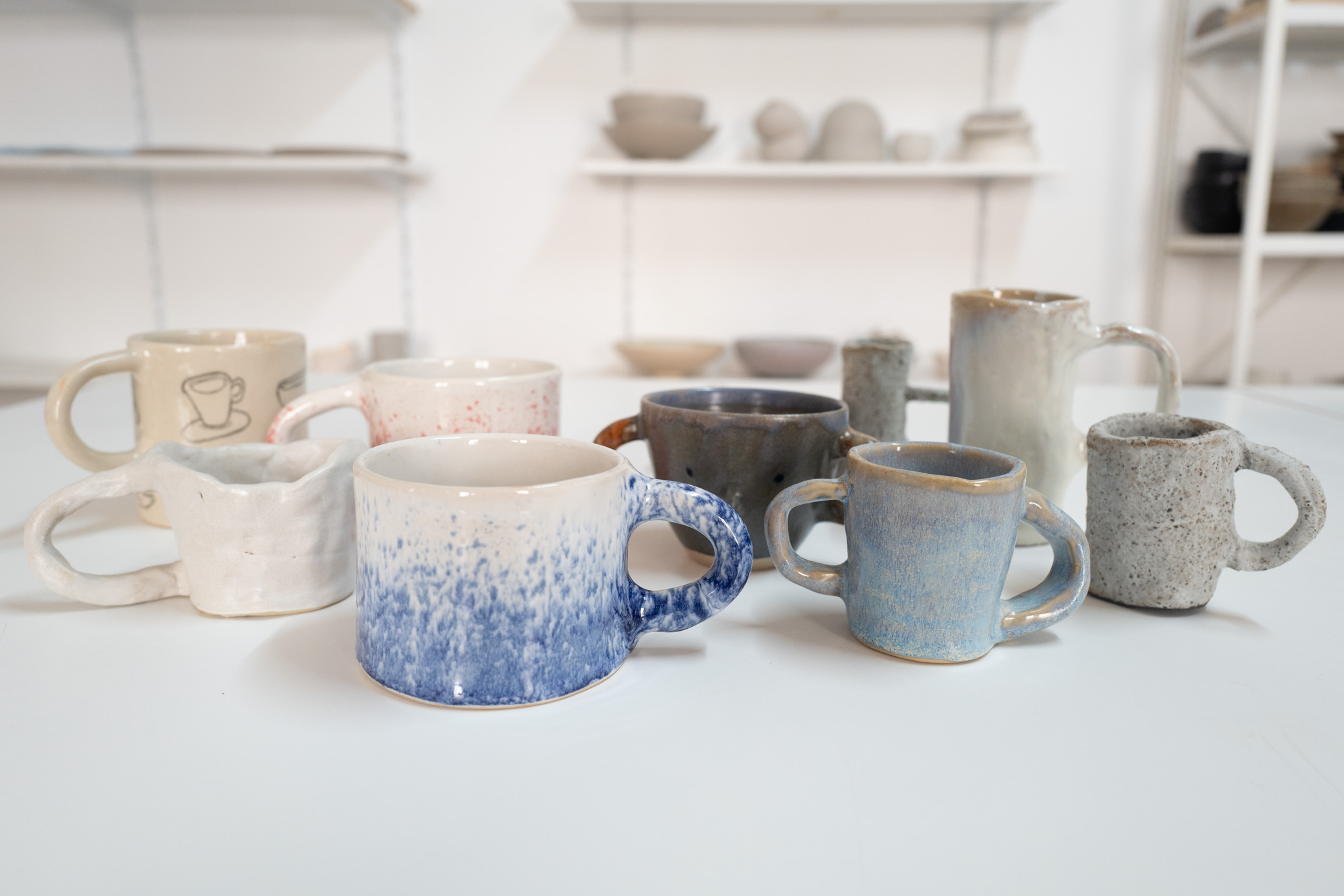 Various handmade mugs on a white table.