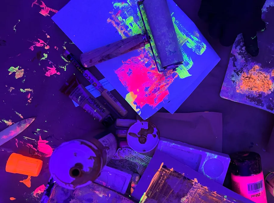 Neonfarben leuchten unter Schwarzlicht in dunklem Raum.