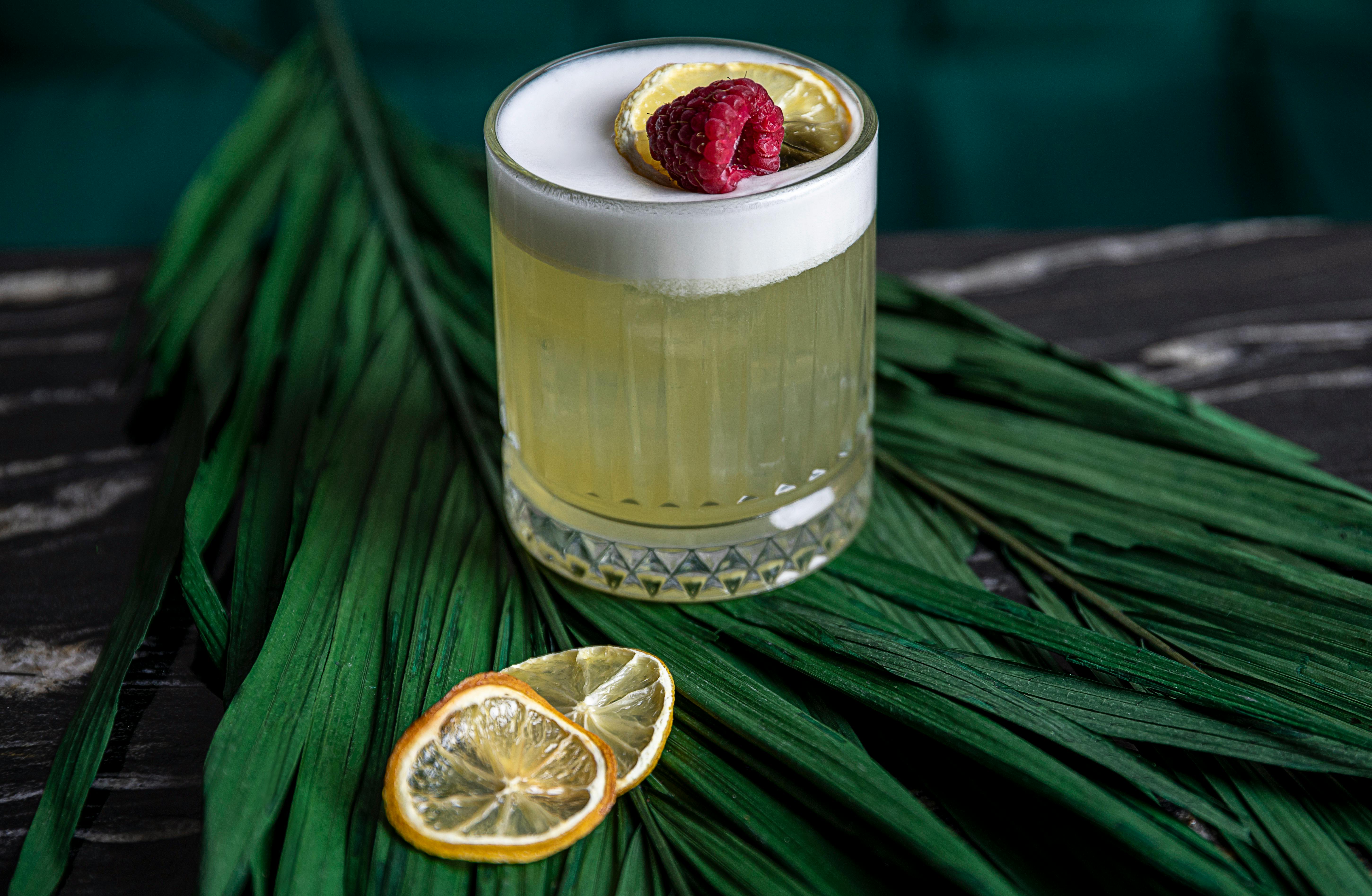 Cocktail mit Schaum und Himbeergarnitur auf Blatt.