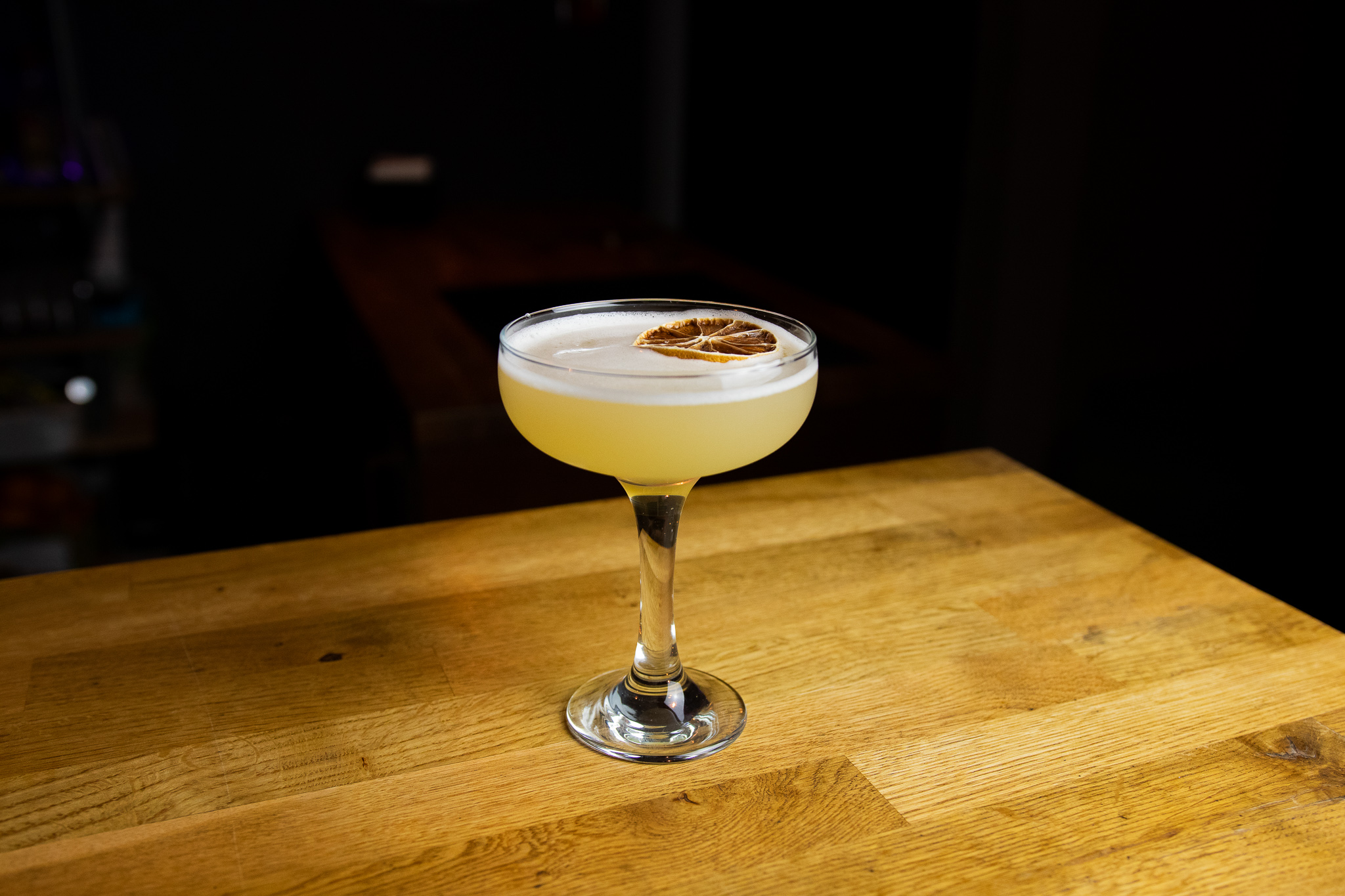 Cocktail glass with dried lime on wooden table.