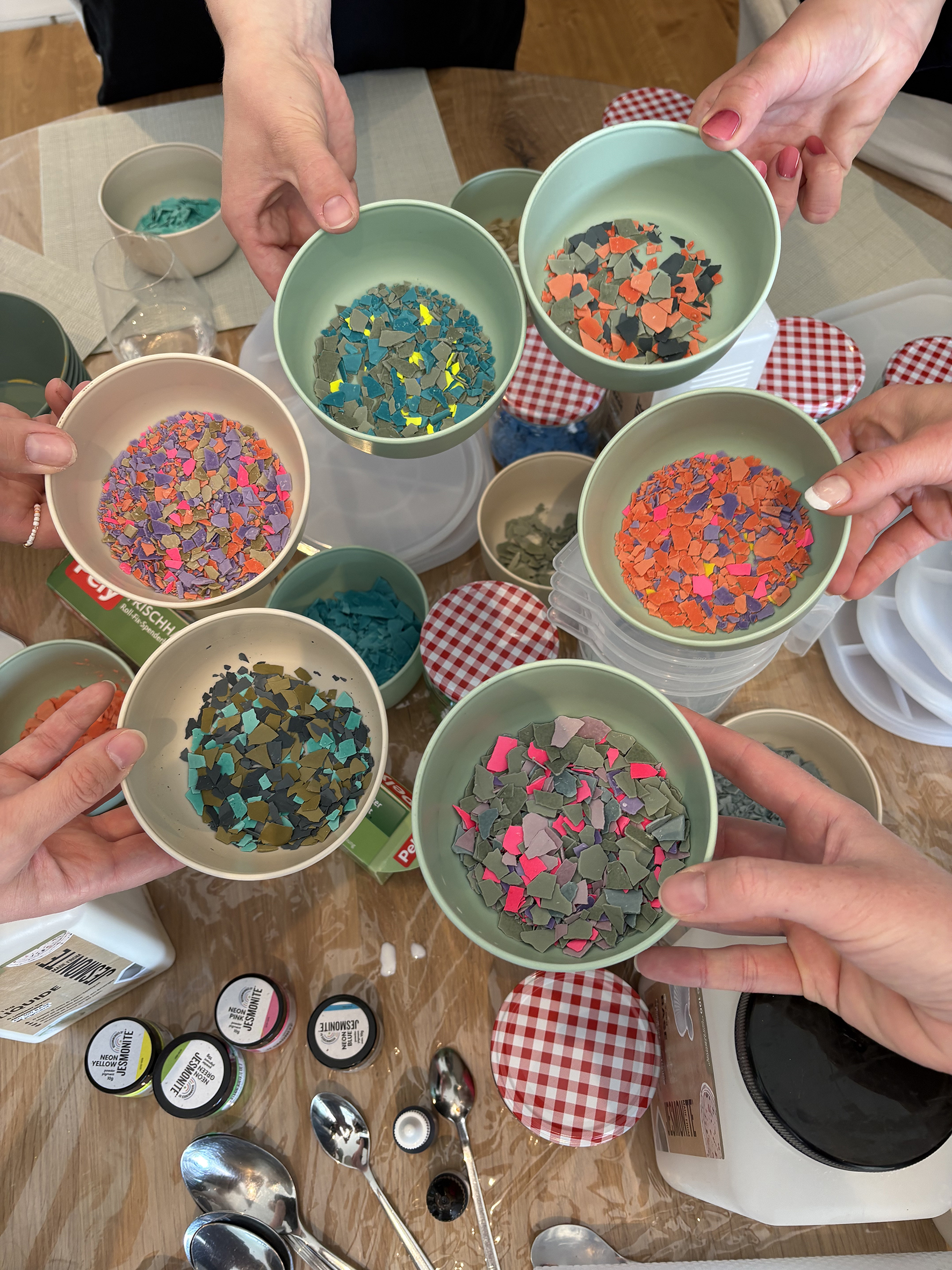Hands holding bowls of colorful plastic pieces.