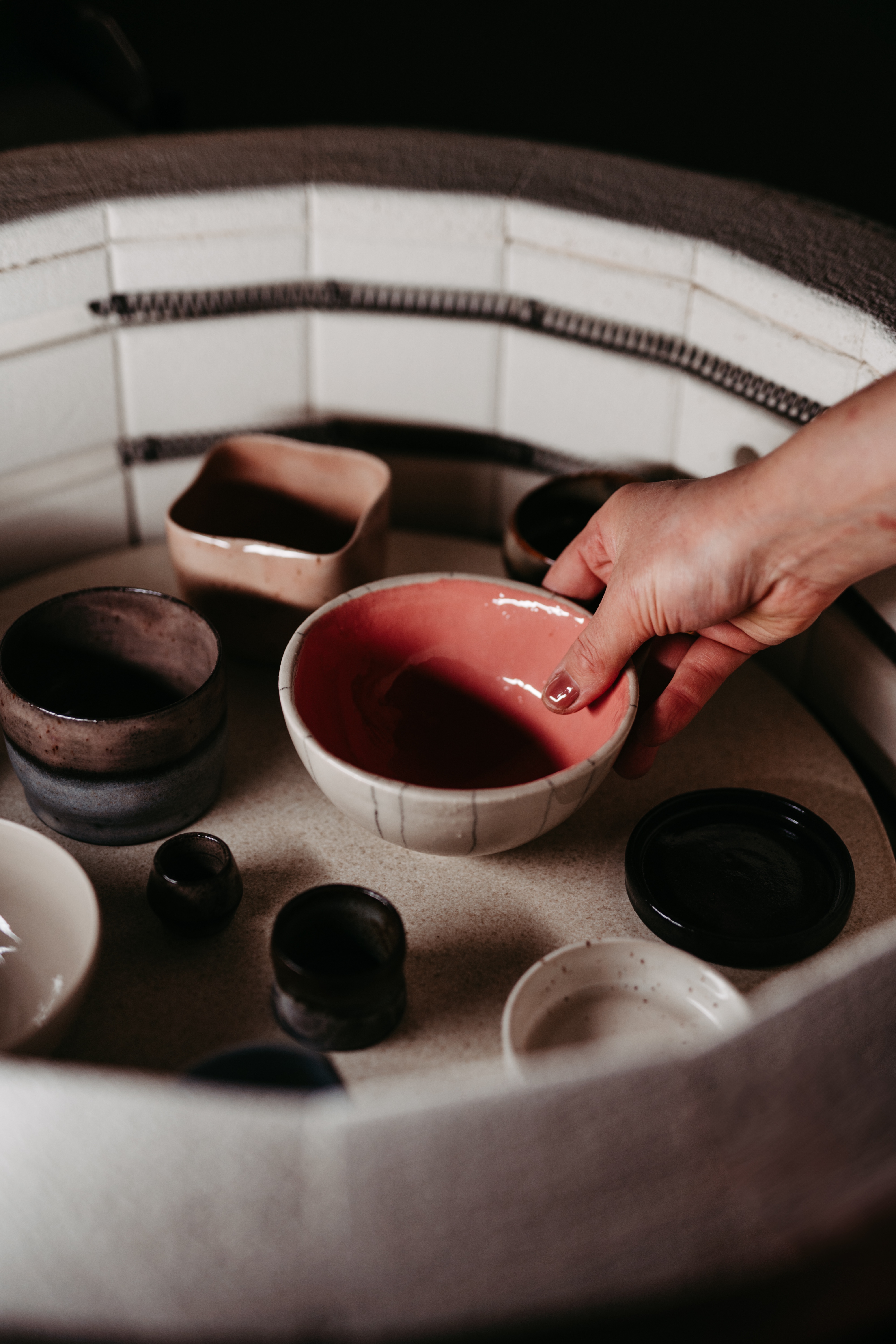 Hand holding ceramic bowl among other pottery.
