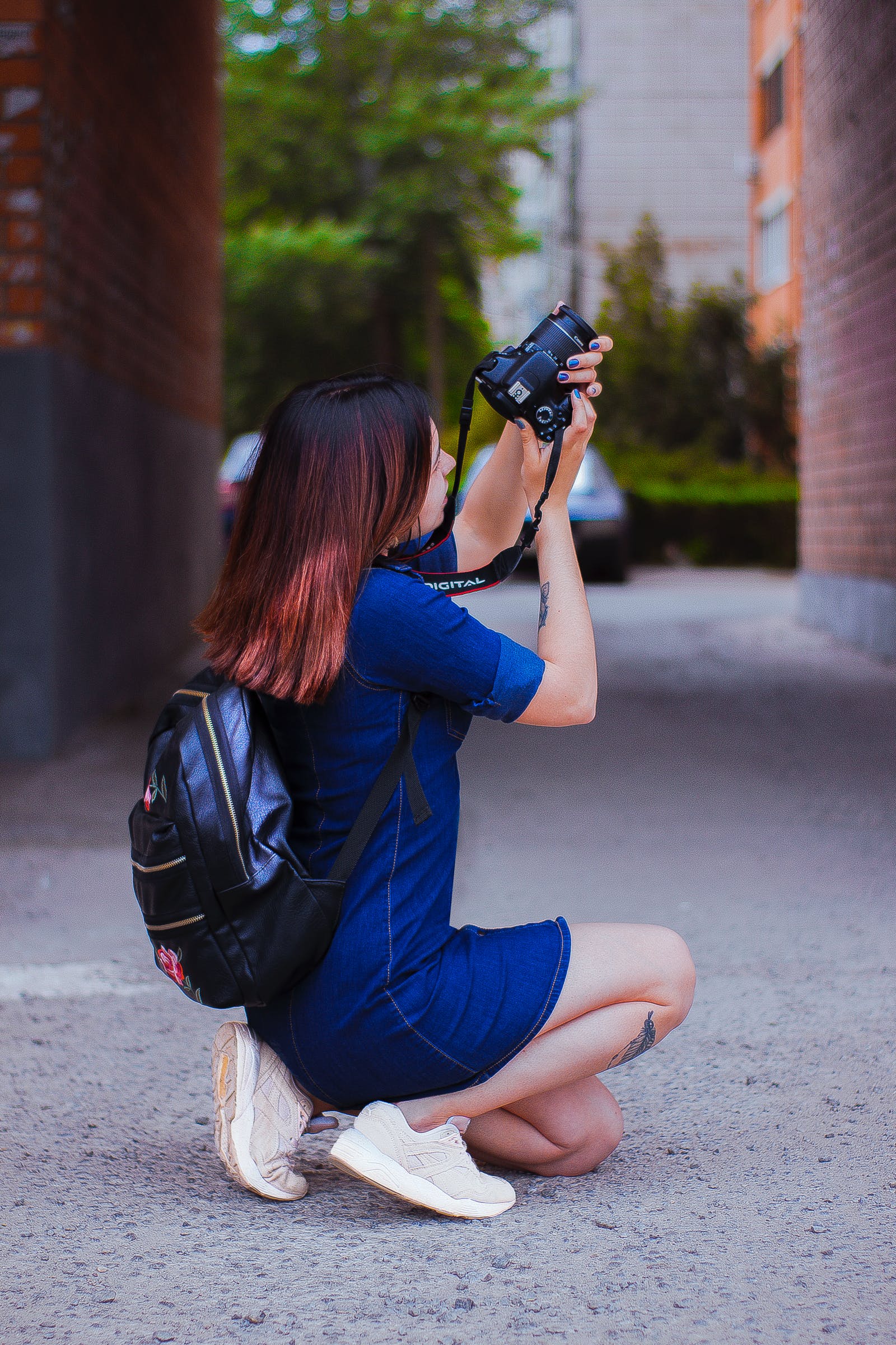 A person takes pictures with a camera in an alley.