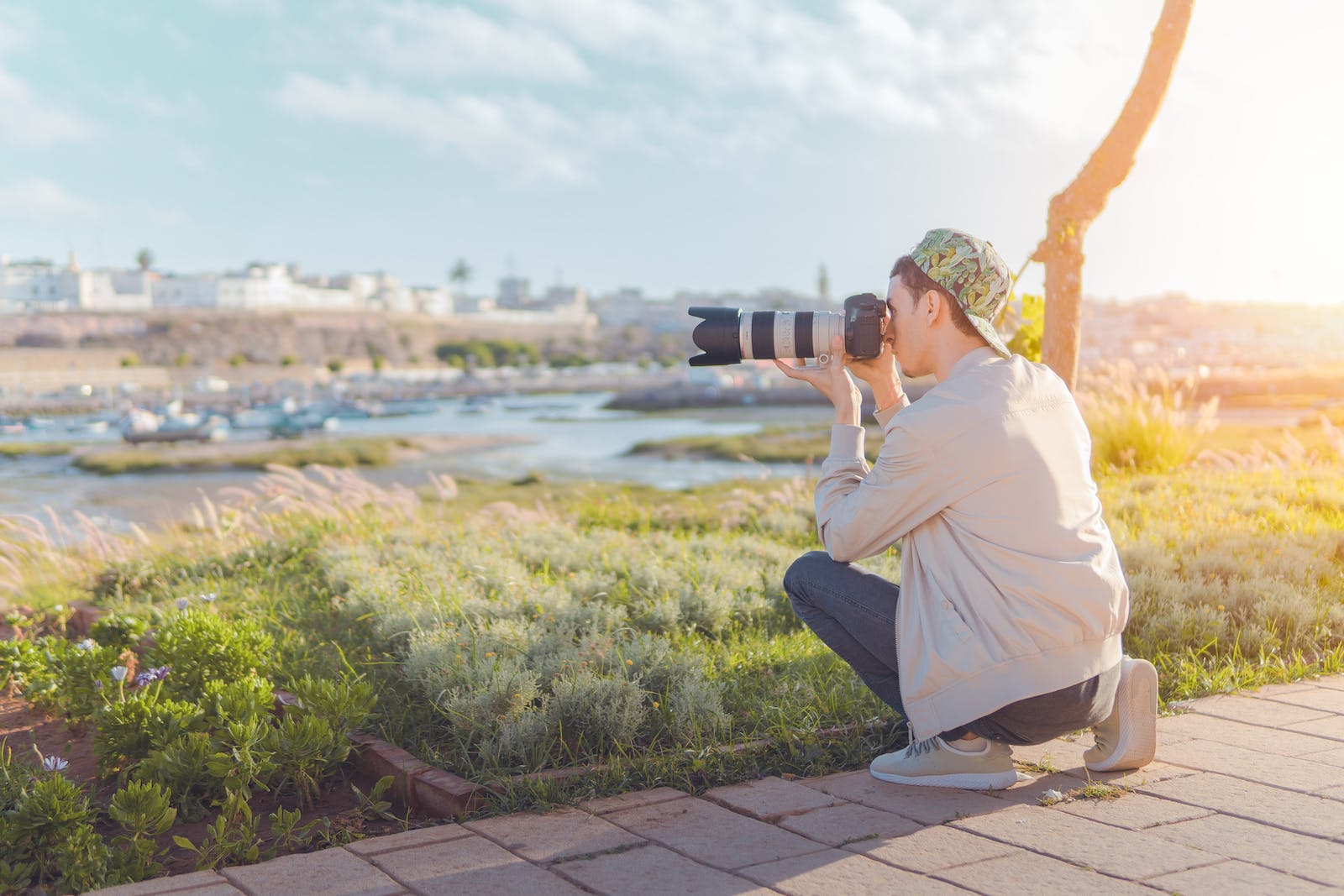 Junger Mann fotografiert mit Kamera in sonniger Landschaft.