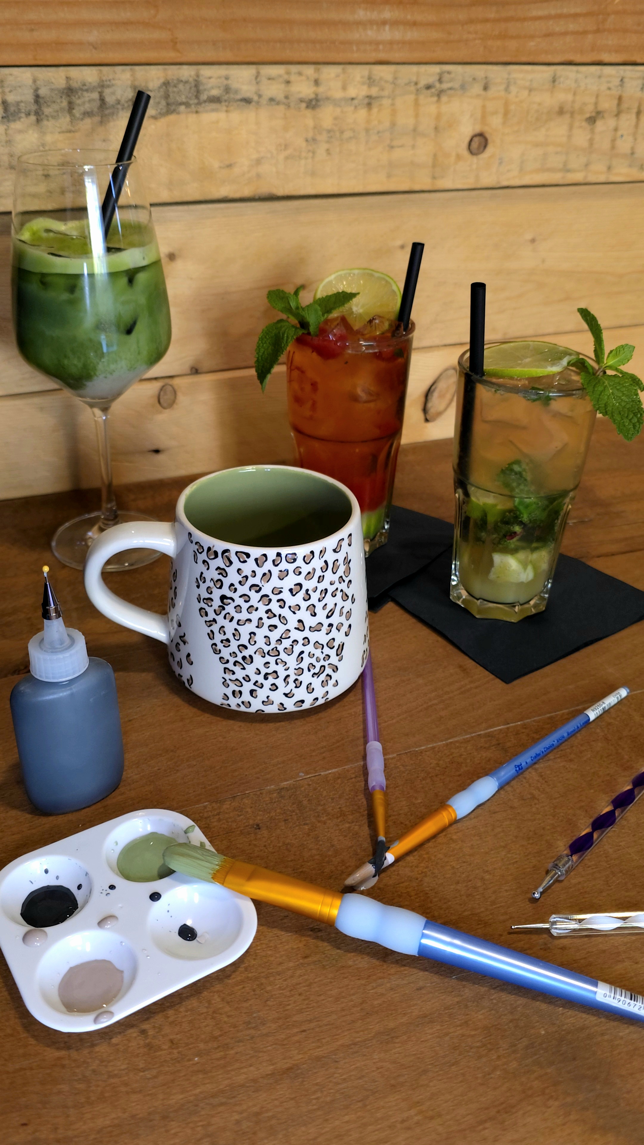 Getränke und bemalte Tasse auf Holztisch.