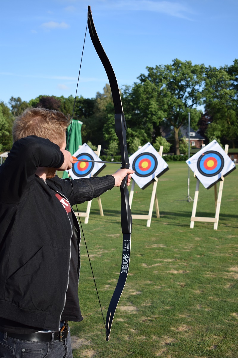 Person aiming bow at archery targets outdoors.