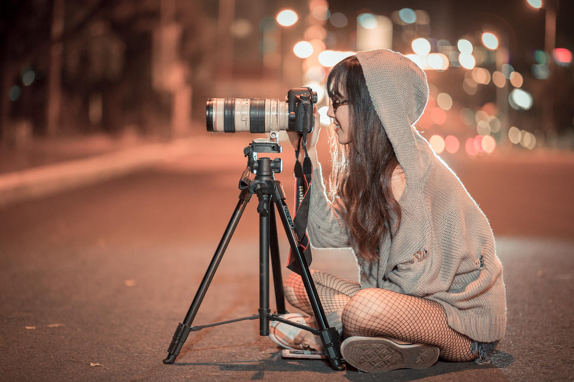 A photographer sits on the street and takes pictures.