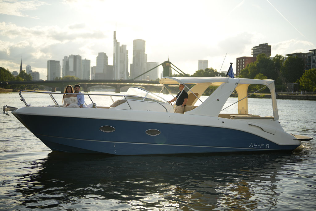 Boat with people on city river at sunset.
