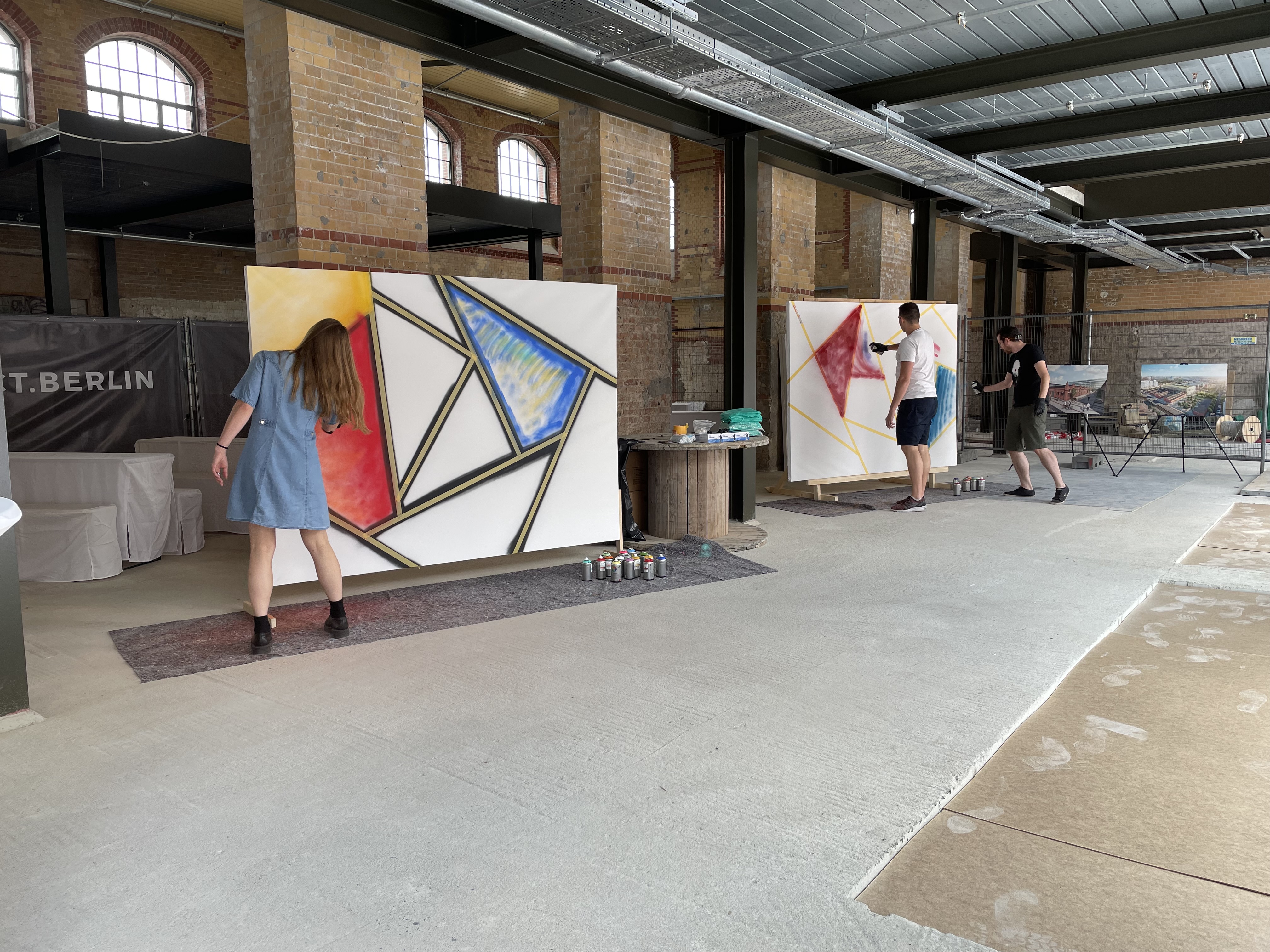 Menschen malen abstrakte Kunst auf großen Leinwänden drinnen.