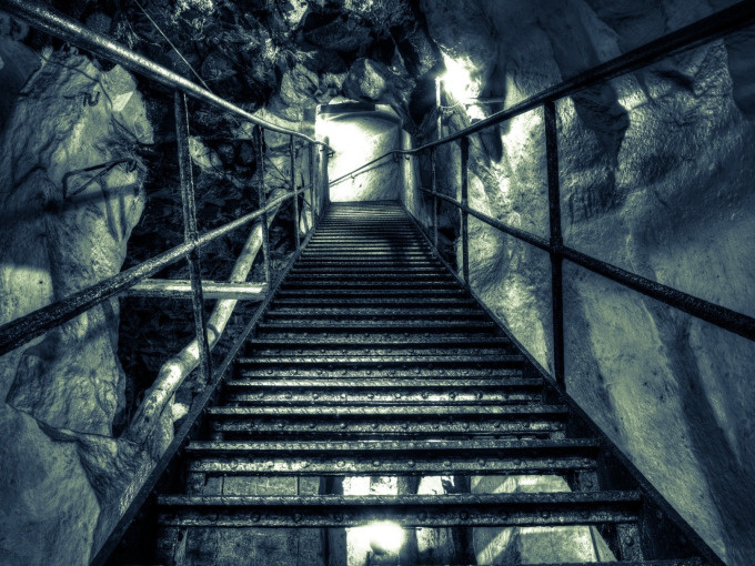 Treppe führt in schwach beleuchtete Höhle.