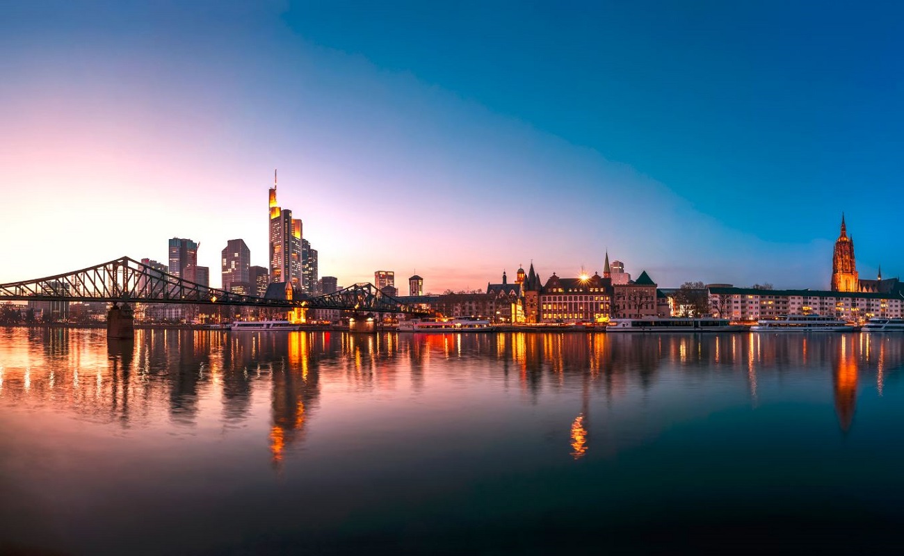 Stadtansicht mit Brücke, reflektiert im Wasser bei Sonnenuntergang.