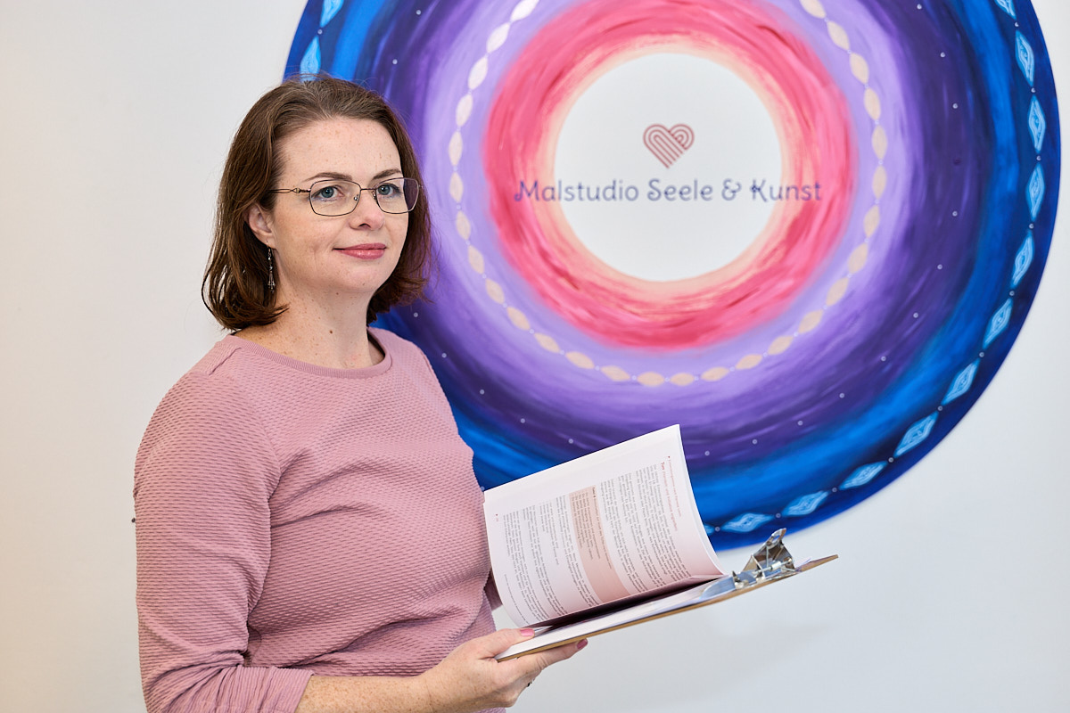 Frau mit Klemmbrett, gemaltes Wandbild im Hintergrund.