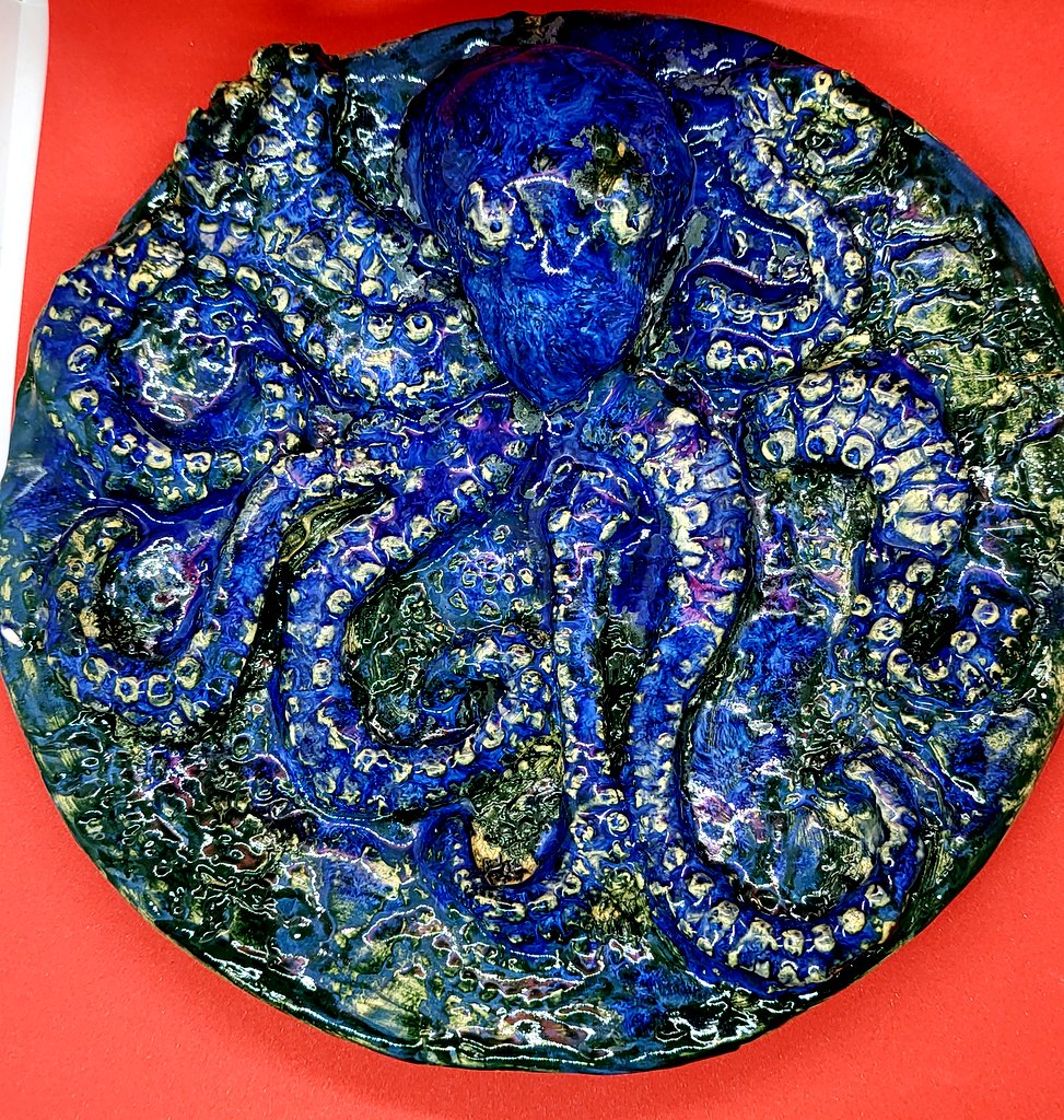 Bunter Keramikteller mit Oktopus auf roter Fläche.