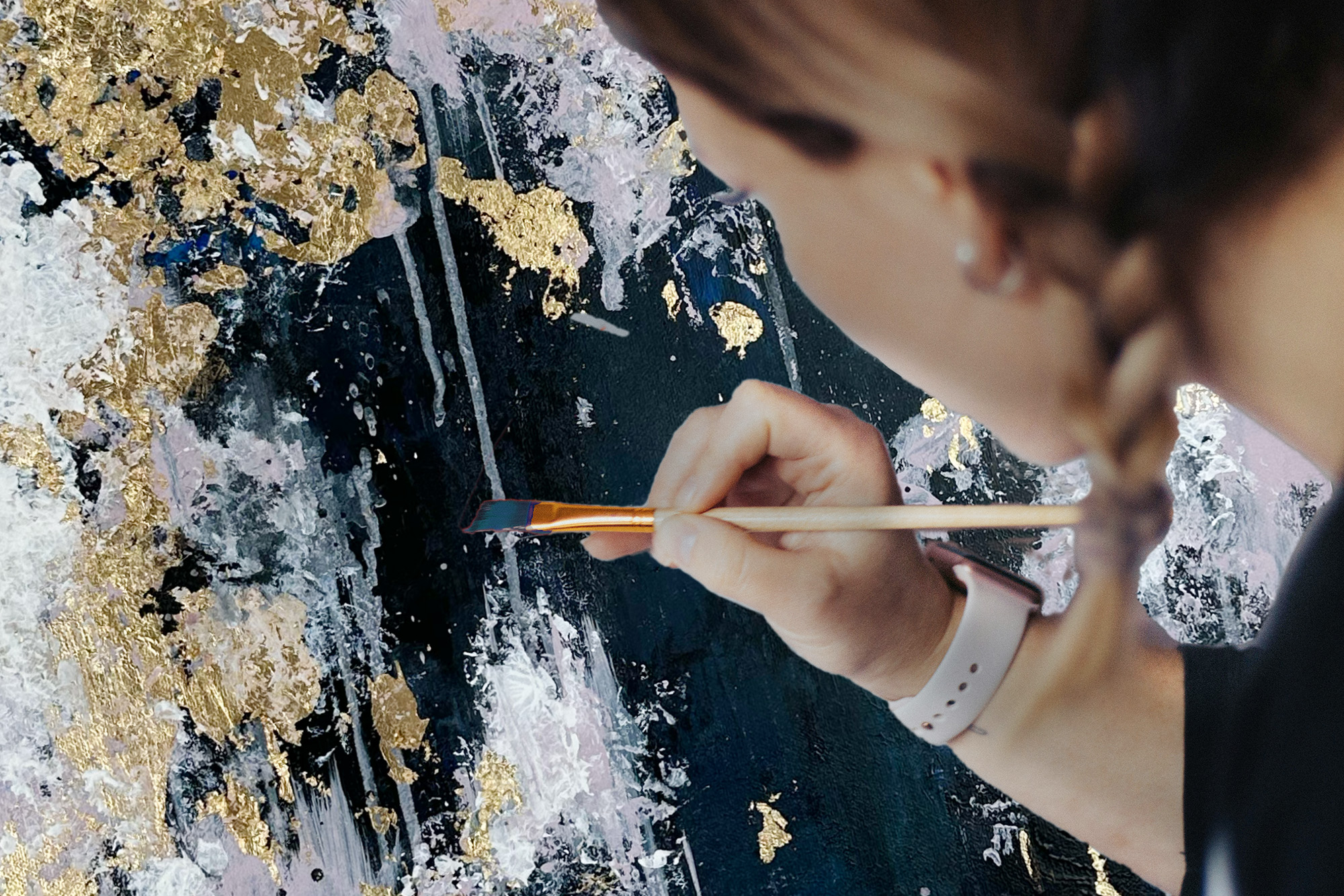 Person malt abstrakte Kunst mit Goldakzenten.