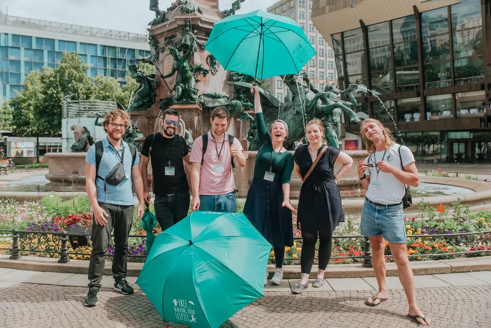 Gruppe mit Regenschirmen auf Stadtplatz.