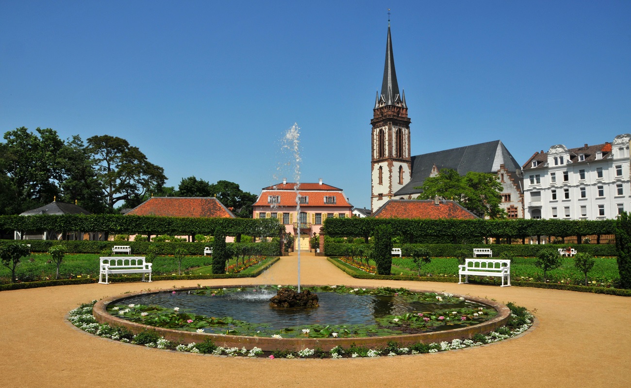 Brunnen sprudelt in einem Garten mit historischen Gebäuden.