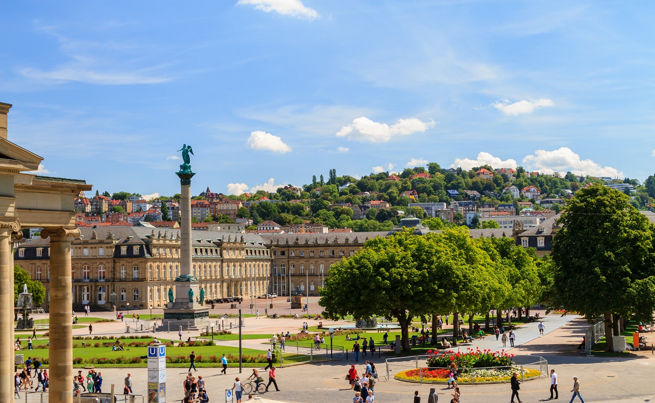 Stadtplatz mit Statue, Menschen spazieren und genießen die Umgebung.