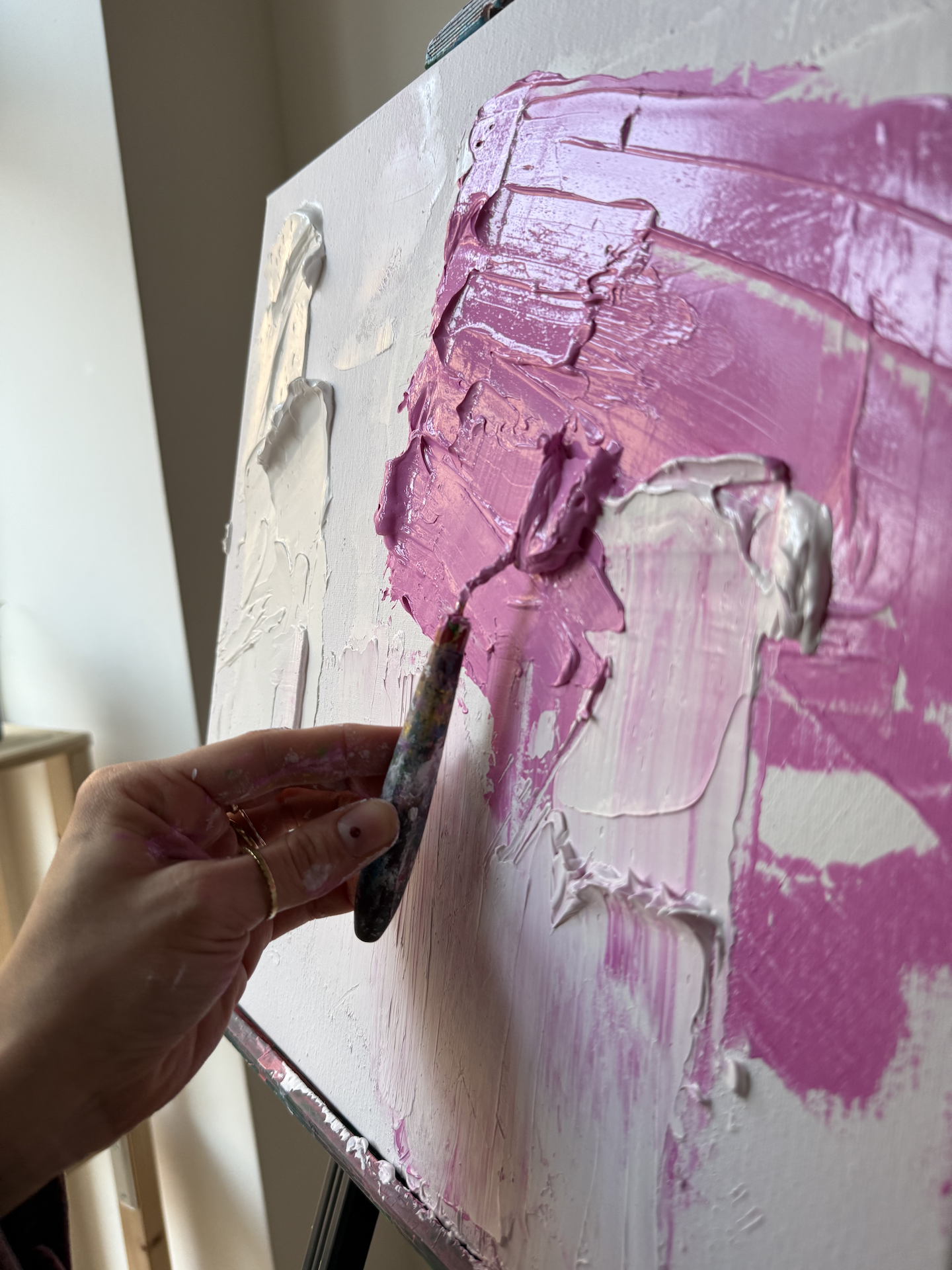 Hand painting on canvas with thick pink paint.