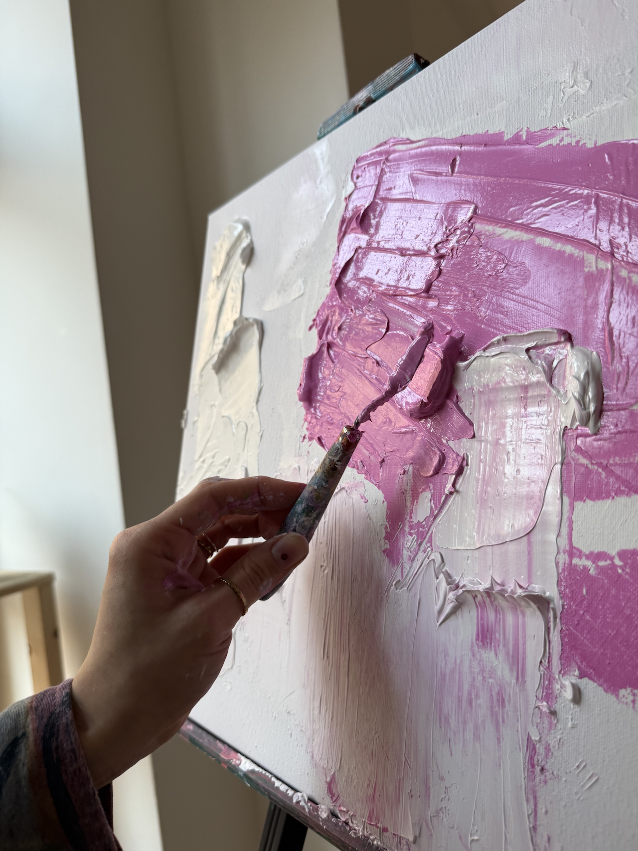 Hand verteilt rosa Farbe auf Leinwand.