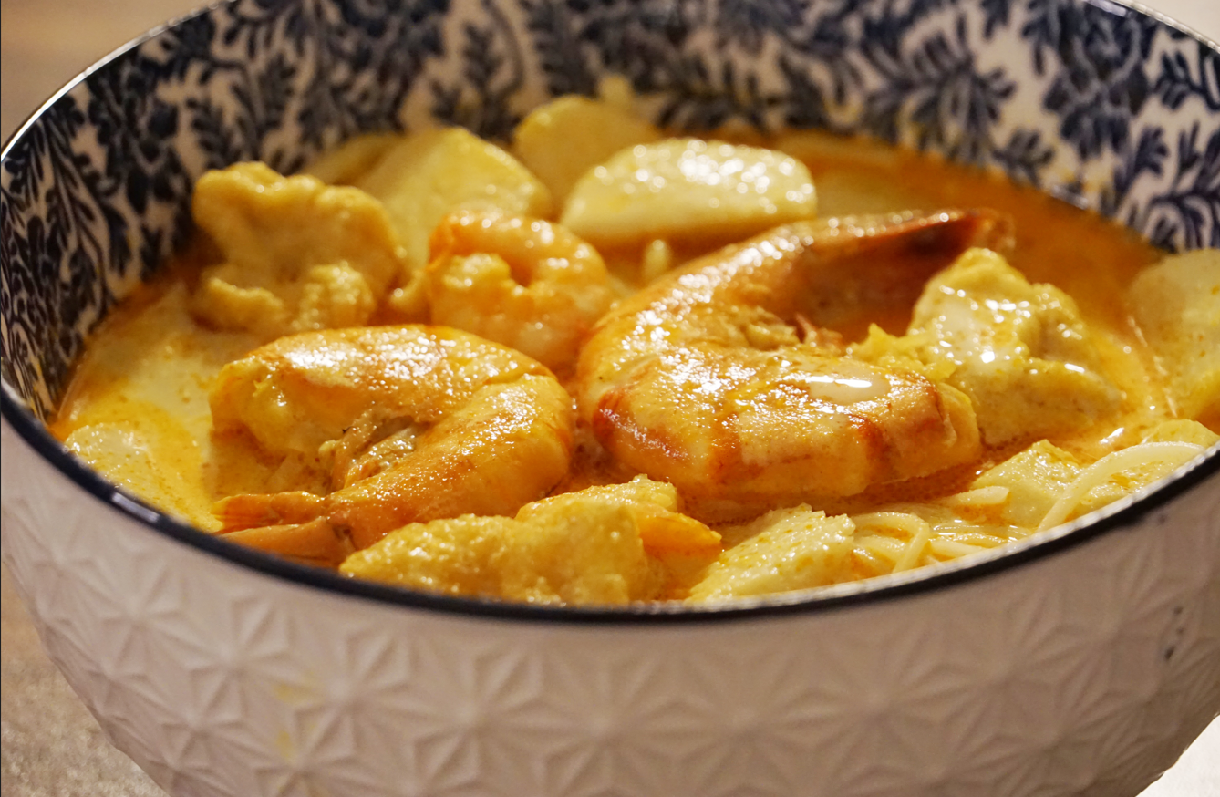 Schüssel mit Garnelen und Nudeln in Currysauce.