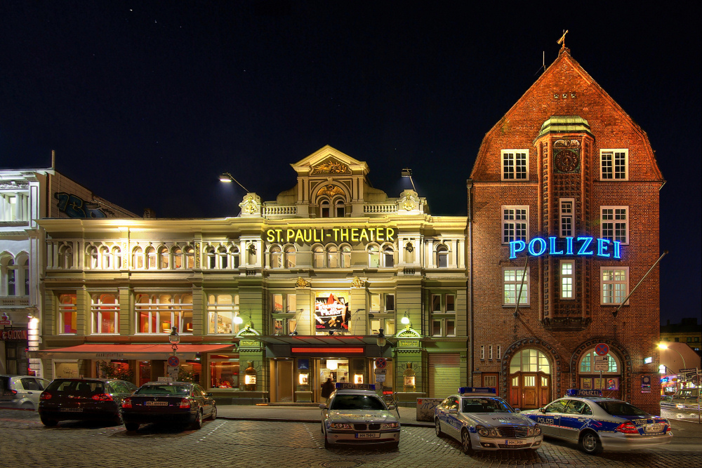 Theater- und Polizeigebäude bei Nacht.