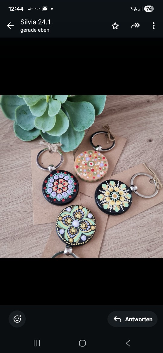 Four colorful mandala keychains on wooden table.