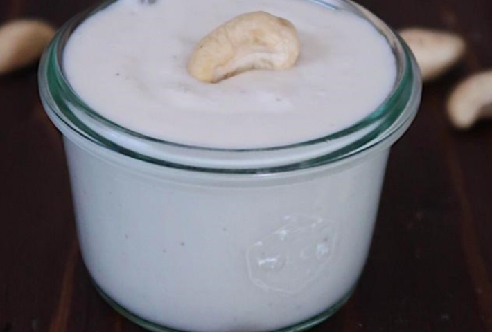 Glass with creamy mass and a cashew nut on top.