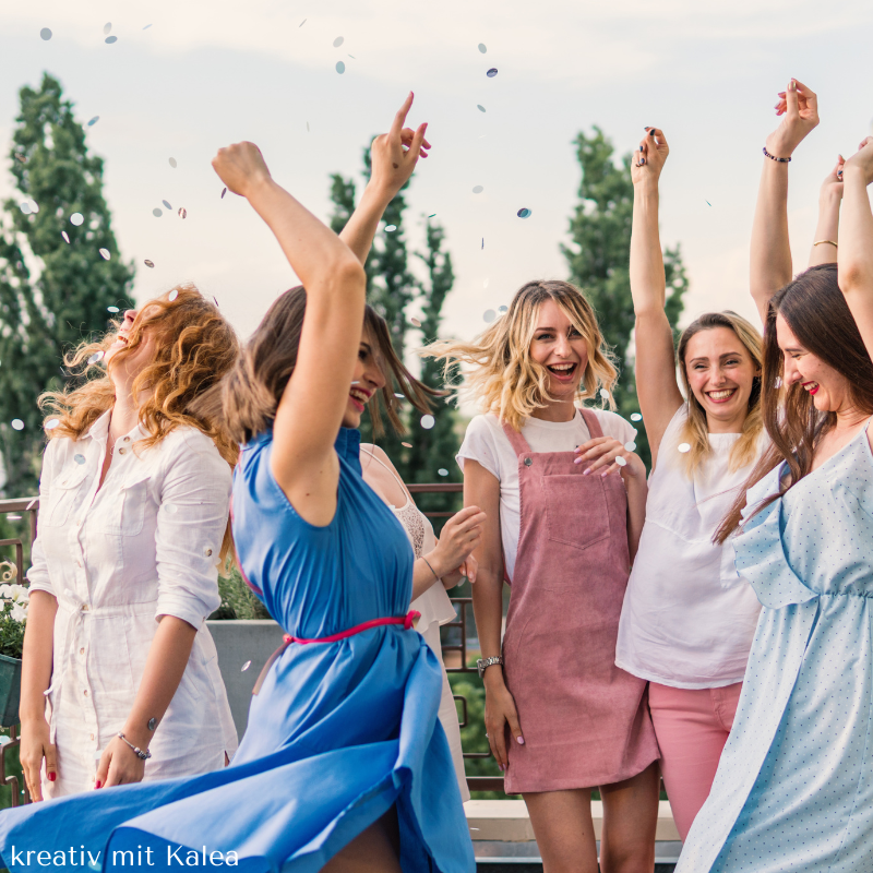 Frauen feiern mit Konfetti im Freien.
