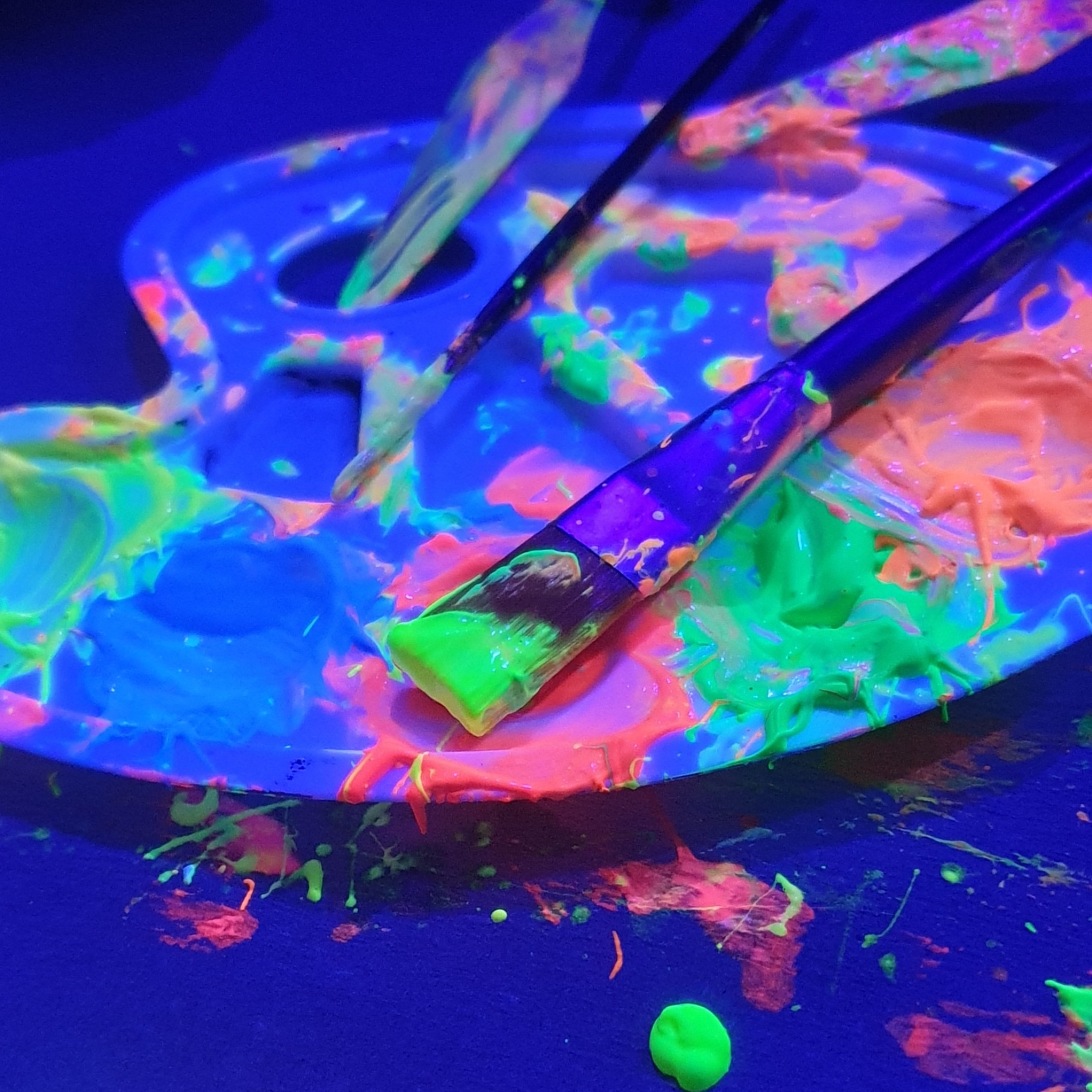 Pinsel auf Palette mit leuchtender Neonfarbe.