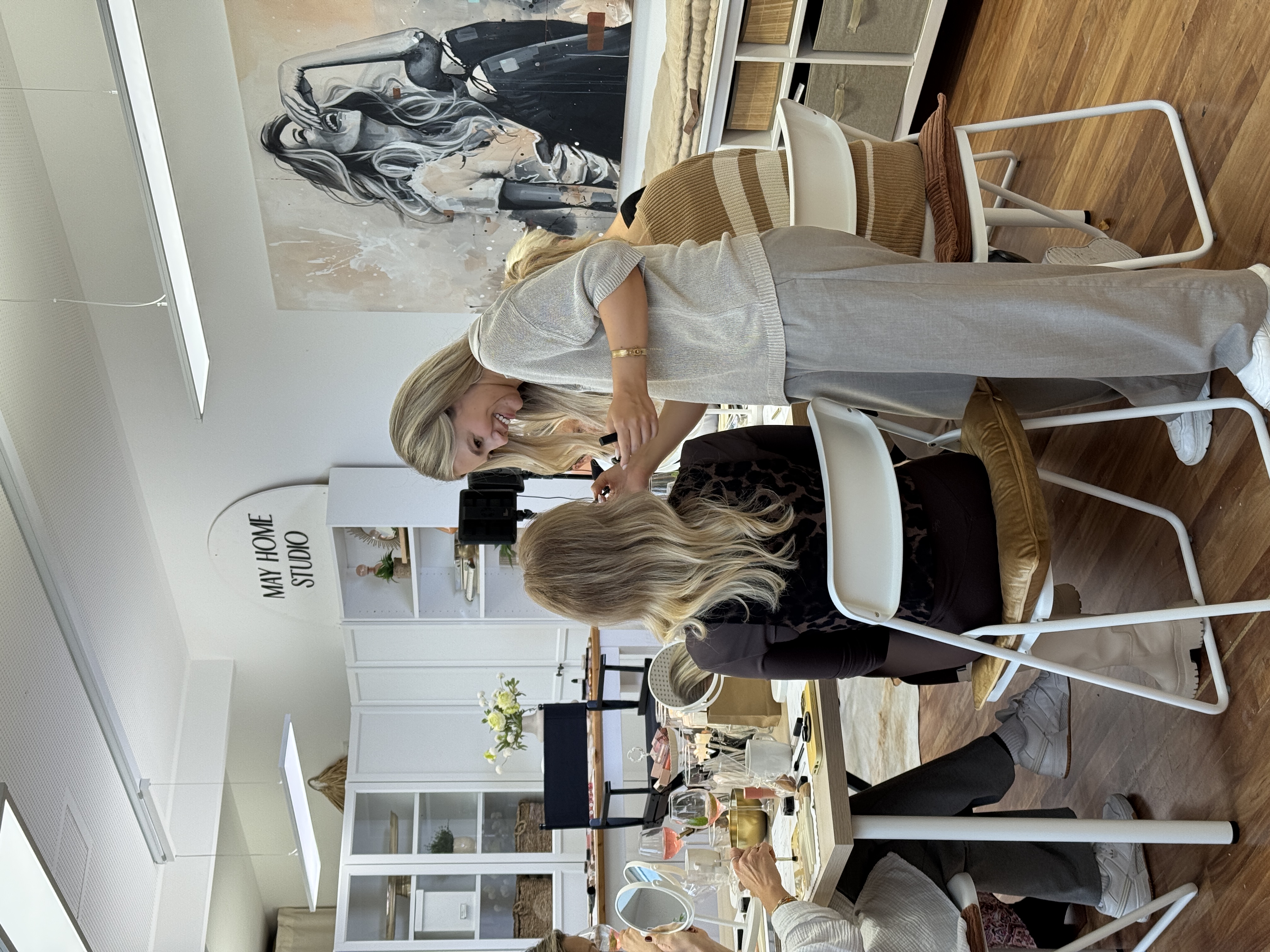 Woman styling another woman's hair in a studio.