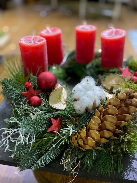 Vier rote Kerzen auf Weihnachtskranzdekoration.
