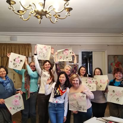 Group of people holding floral paintings indoors.