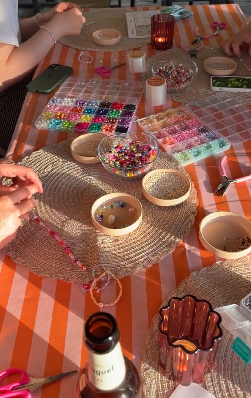 Hands crafting with colorful beads on table.