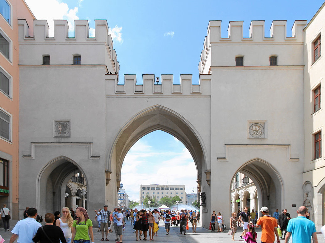 Menschen gehen durch historisches Stadttor.