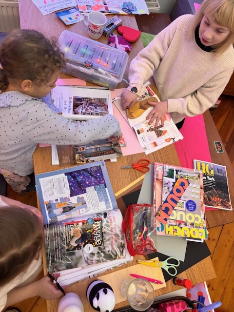 Kinder basteln mit Zeitschriften am Tisch.