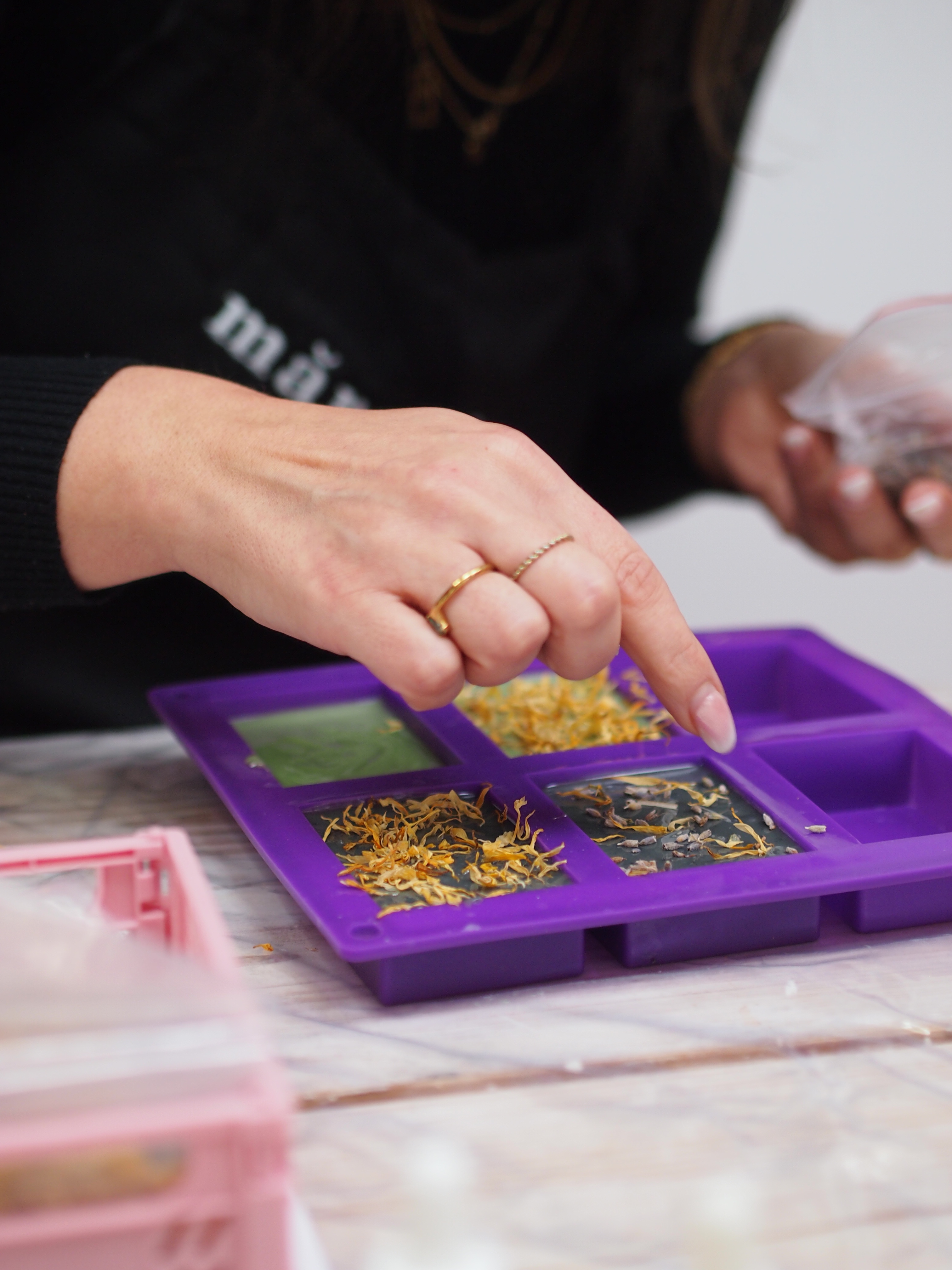 Hand platziert Zutaten in Seifenformbehälter.