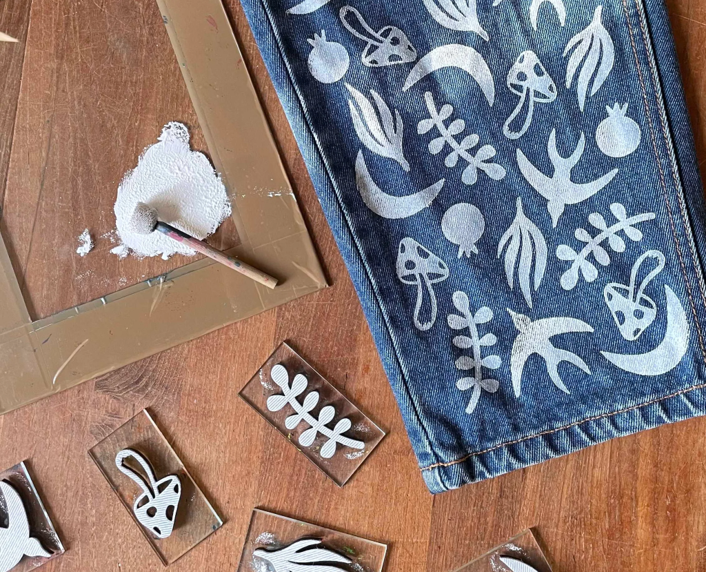 Denim mit weißen botanischen Designs bemalt.