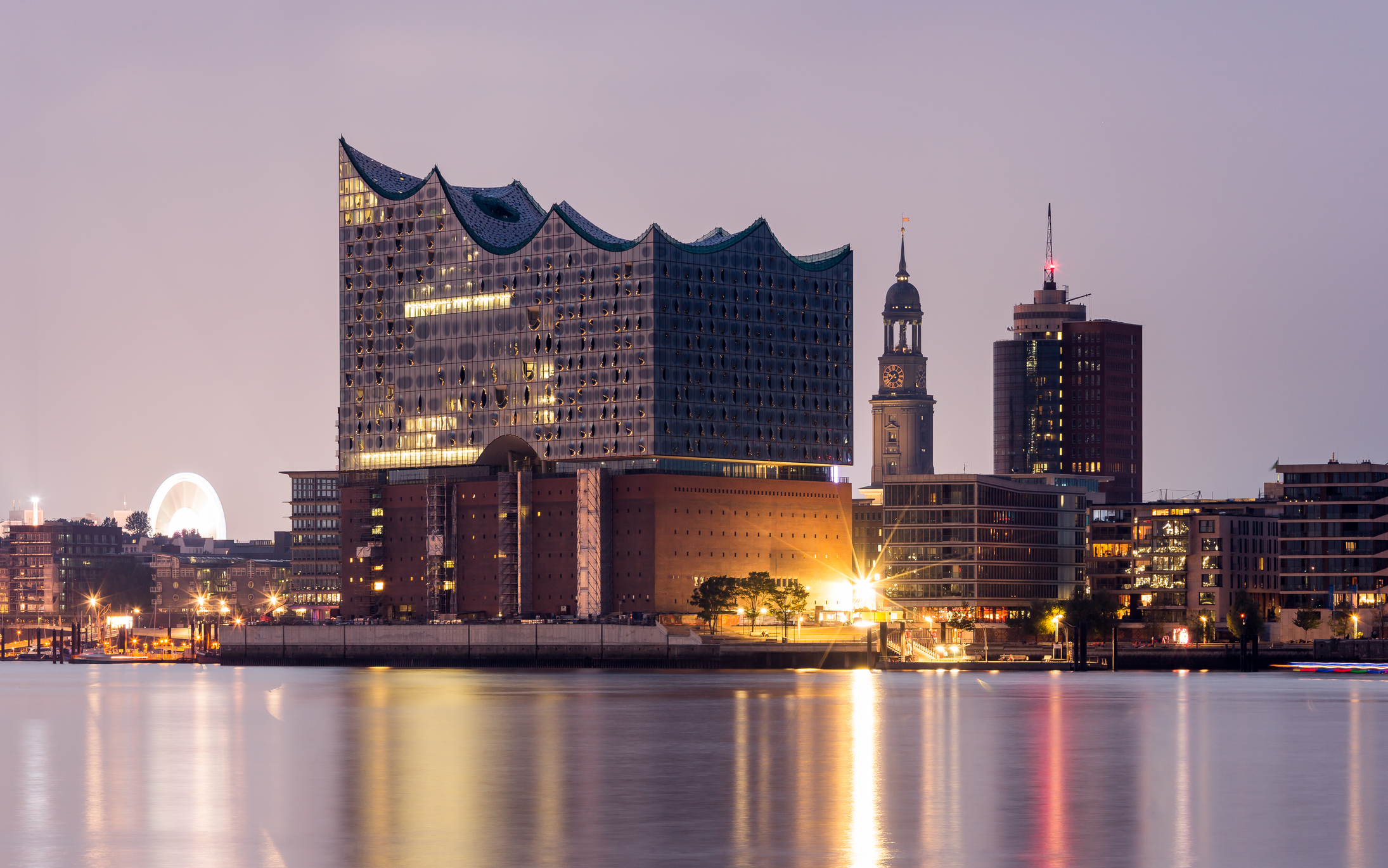 Modernes Konzerthaus am Wasser bei Dämmerung.
