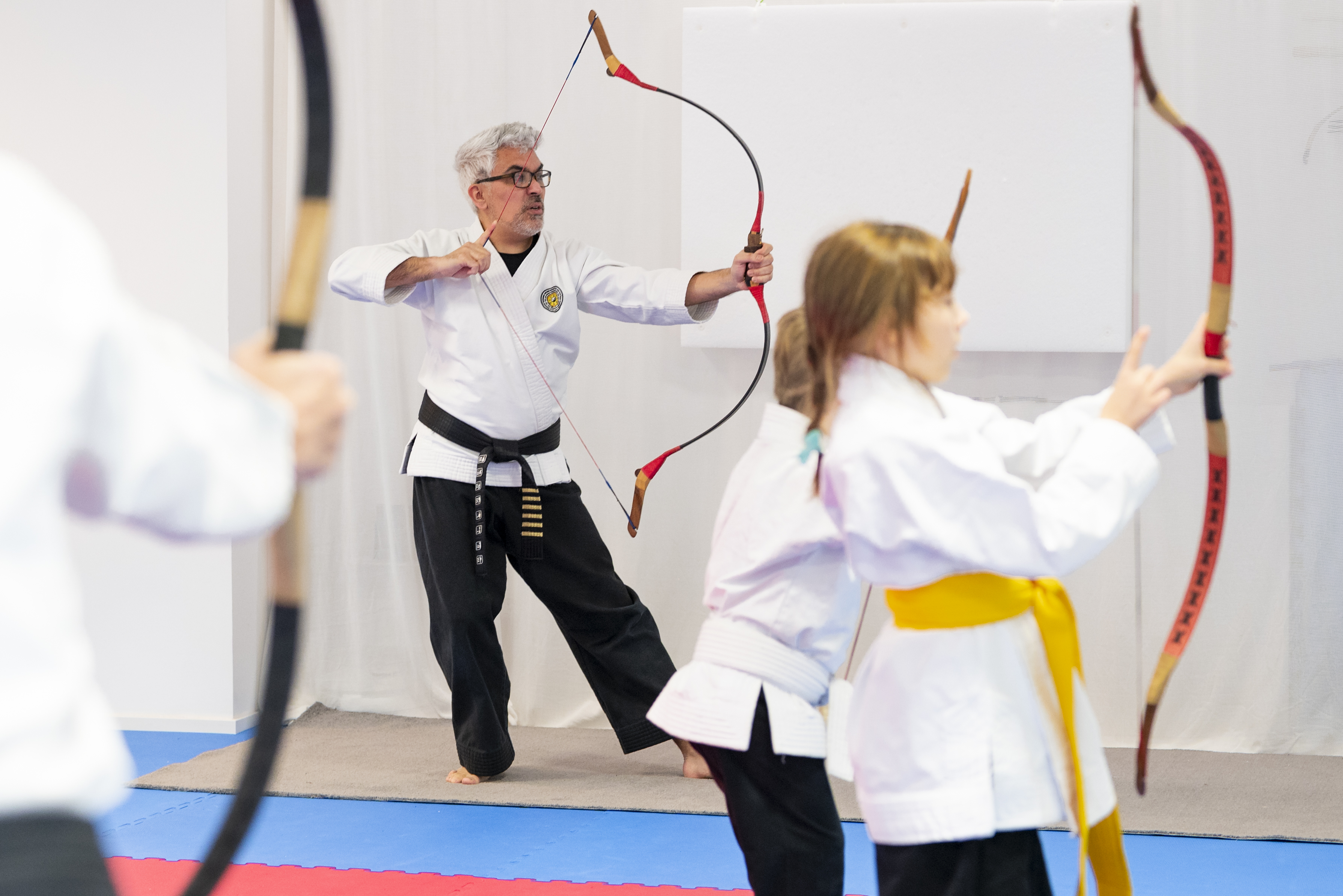 Personen üben Bogenschießen im Kampfsportkurs.